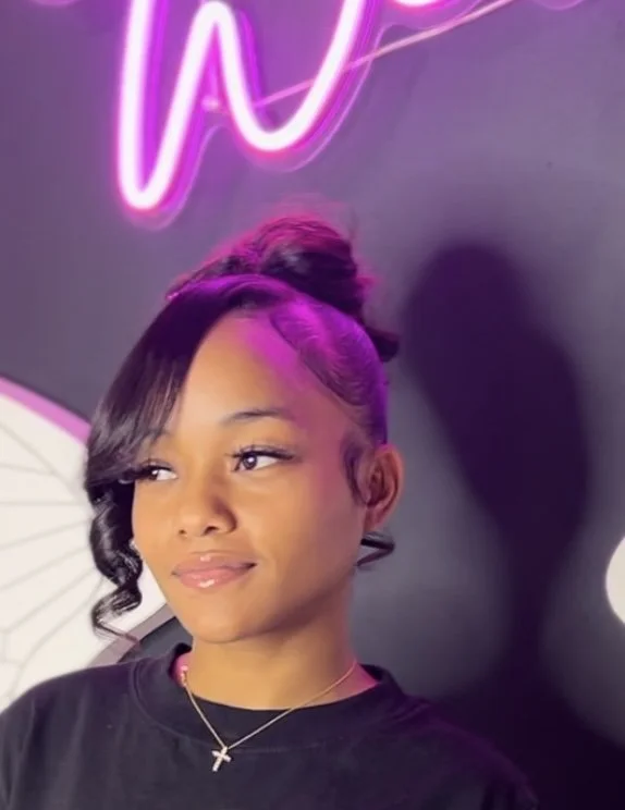 Client wearing an elegant high bun hairstyle with side-swept curls at Salon de Weave.