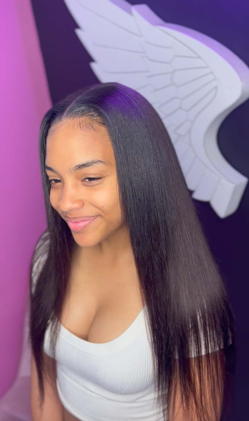 Young woman with straight black hair smiling in front of a purple and black background with a wing mural.