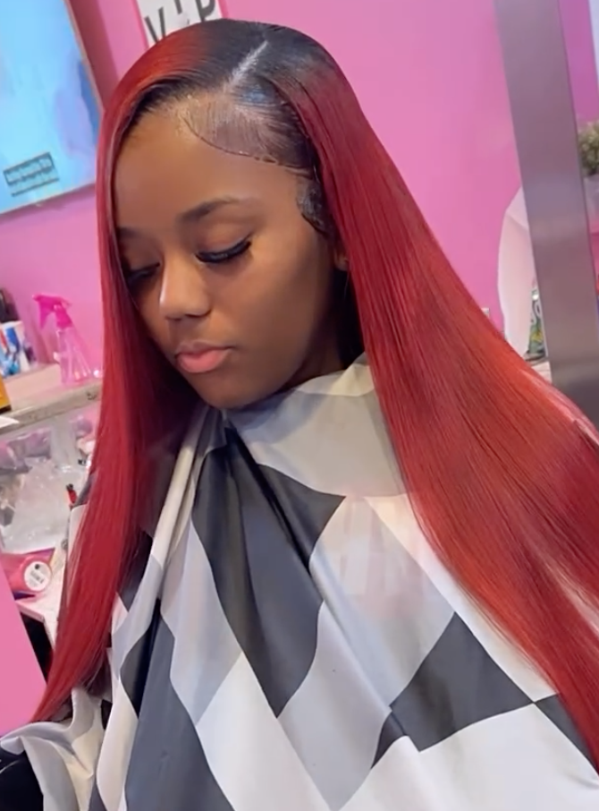 Client with long, vibrant red hair after a professional color service at Salon de Weave.