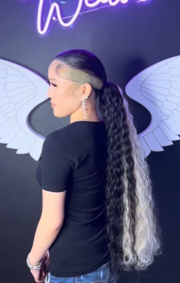 Client wearing a sleek ponytail with custom hair color and long waves at Salon de Weave.