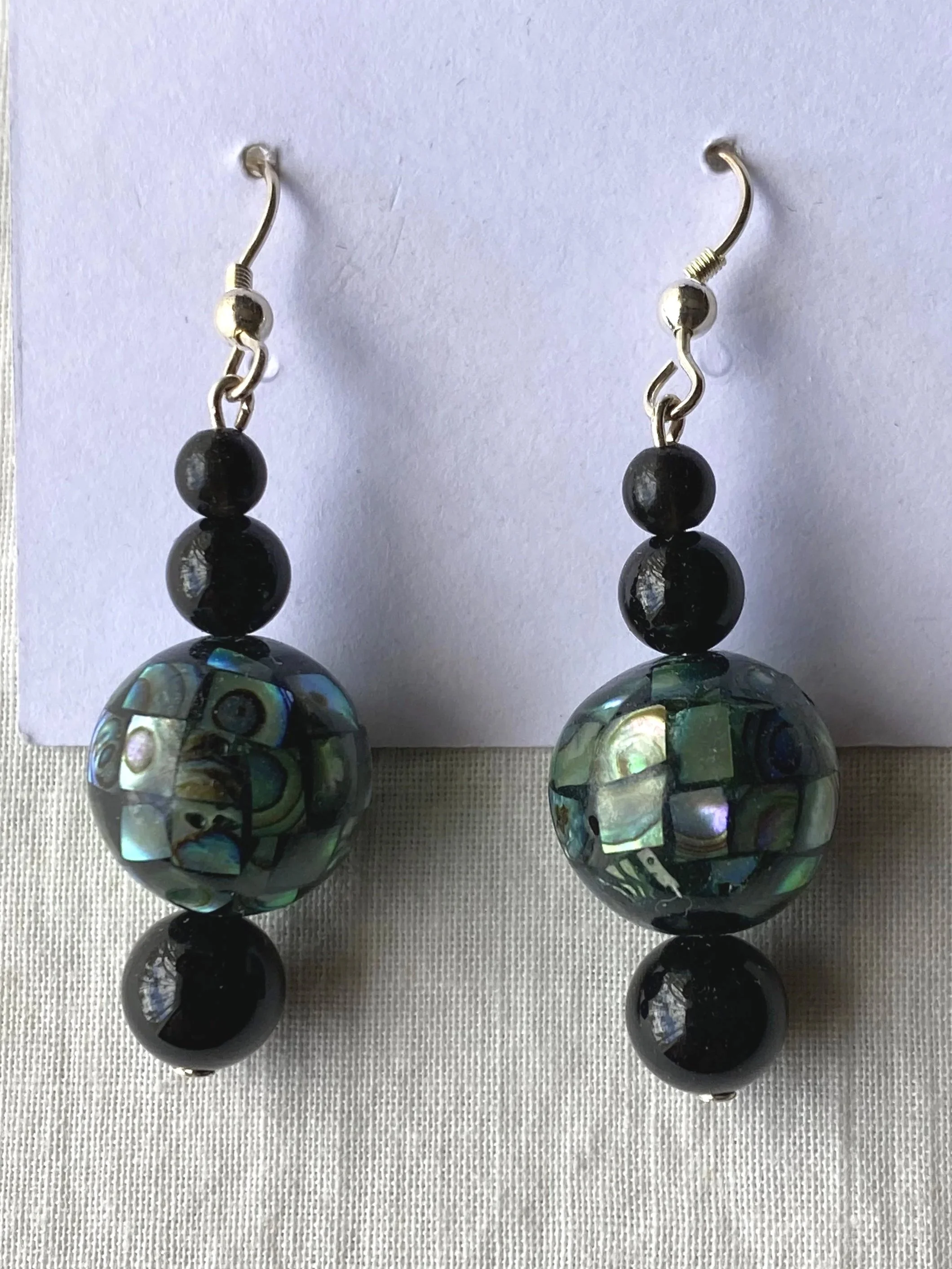 Pair of earrings with black beads and large spherical abalone shell pendants.