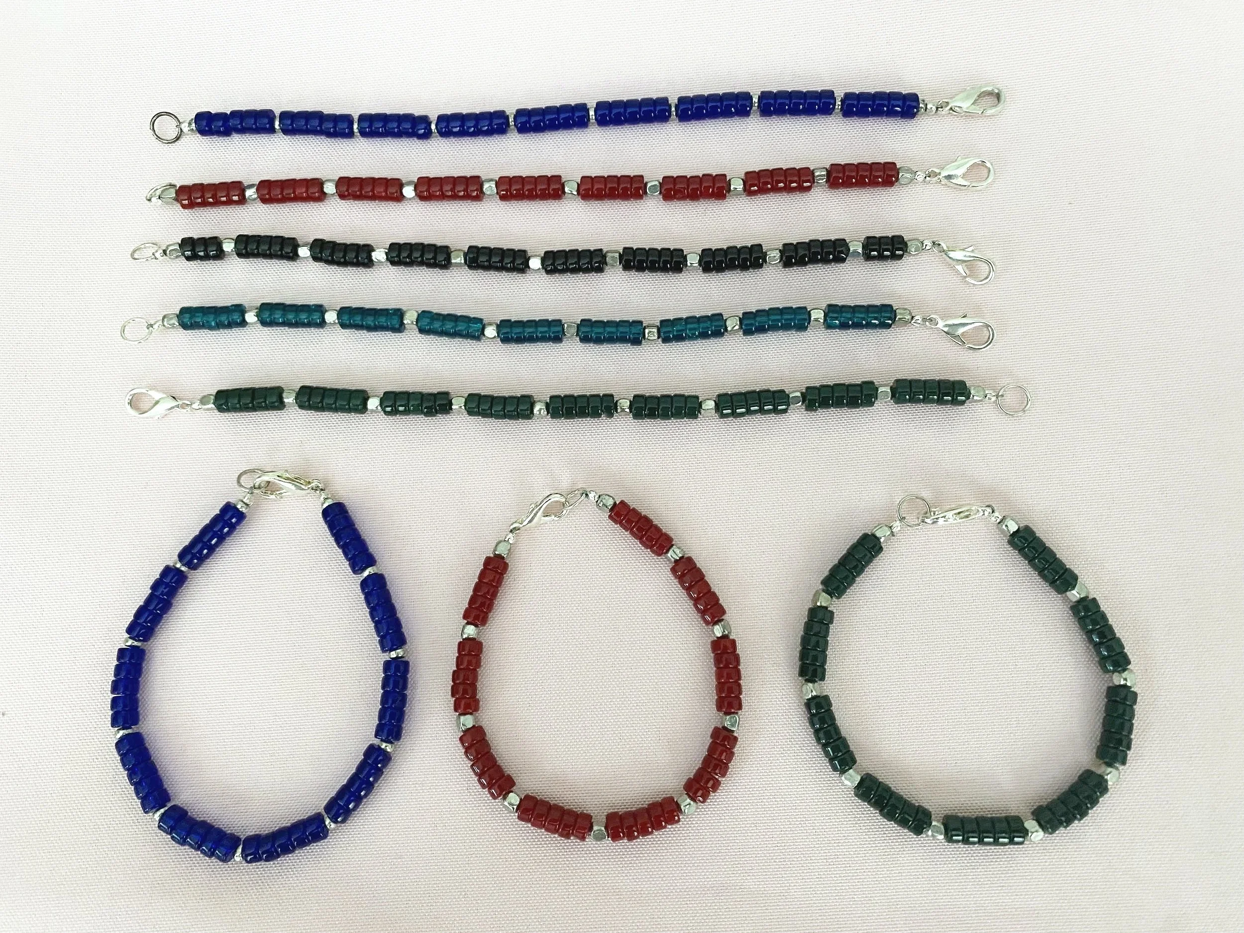 Several beaded necklaces with lobster clasps, including blue, red, black, teal, and green colors, laid out on a white background.
