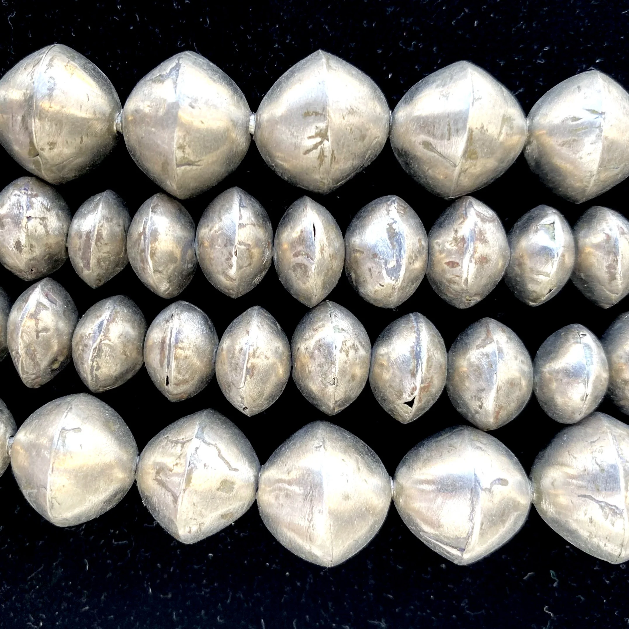 A row of silver metallic spheres beads arranged on a black surface.