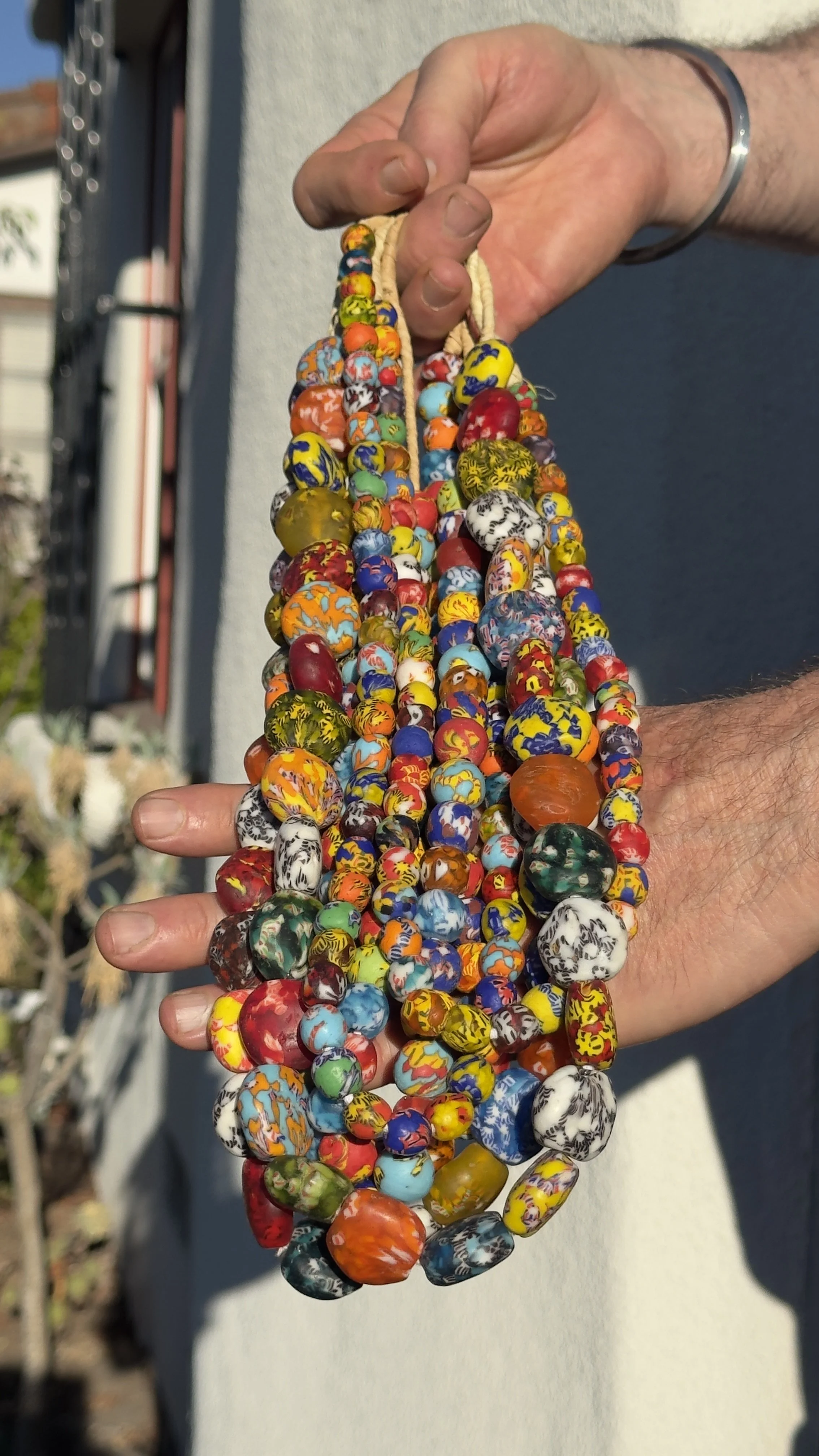 Hands holding multiple colorful strands of beads.