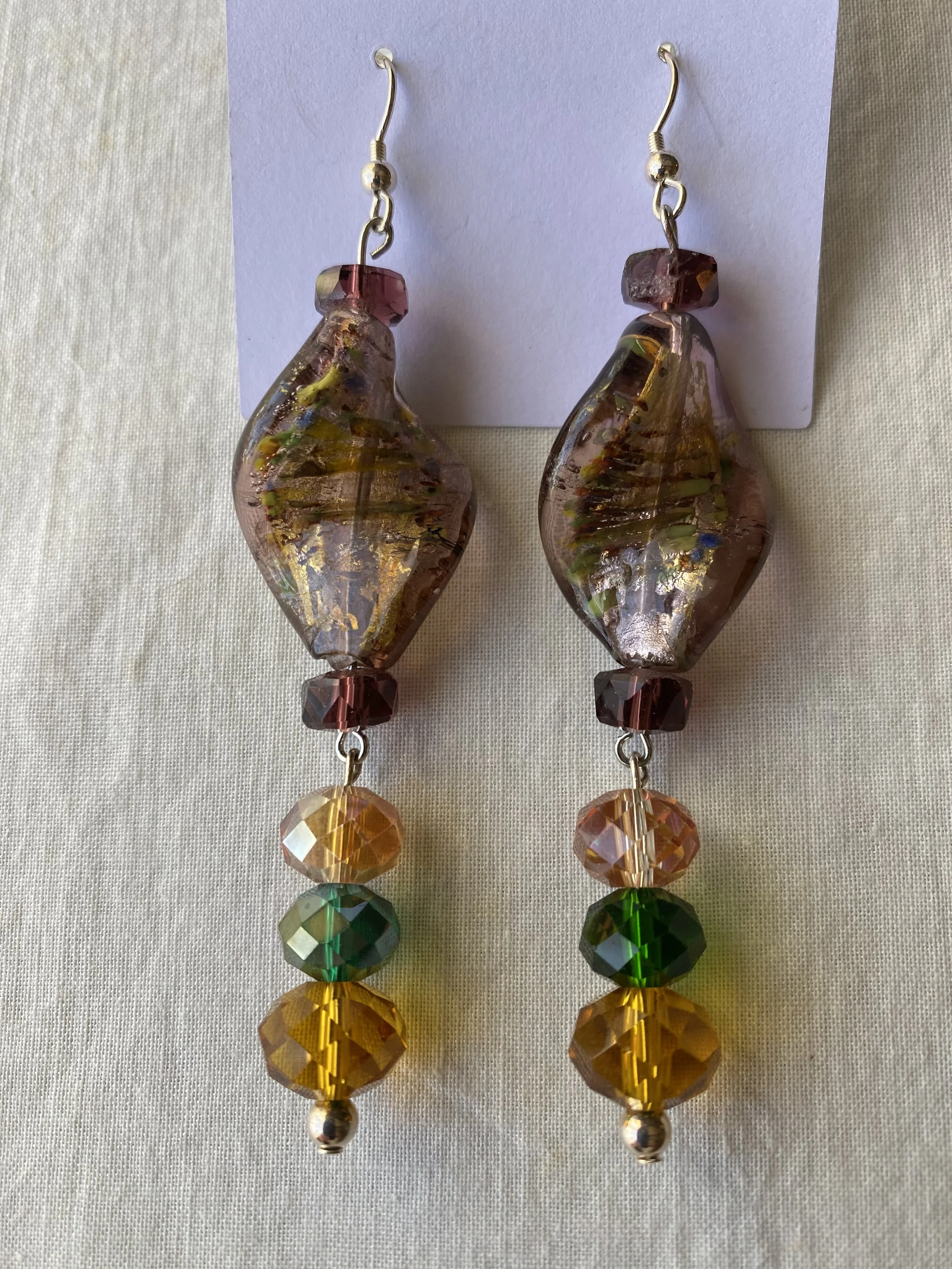 Colorful beaded earrings with large glass beads, smaller faceted beads, and metal accents, hanging against a white background.