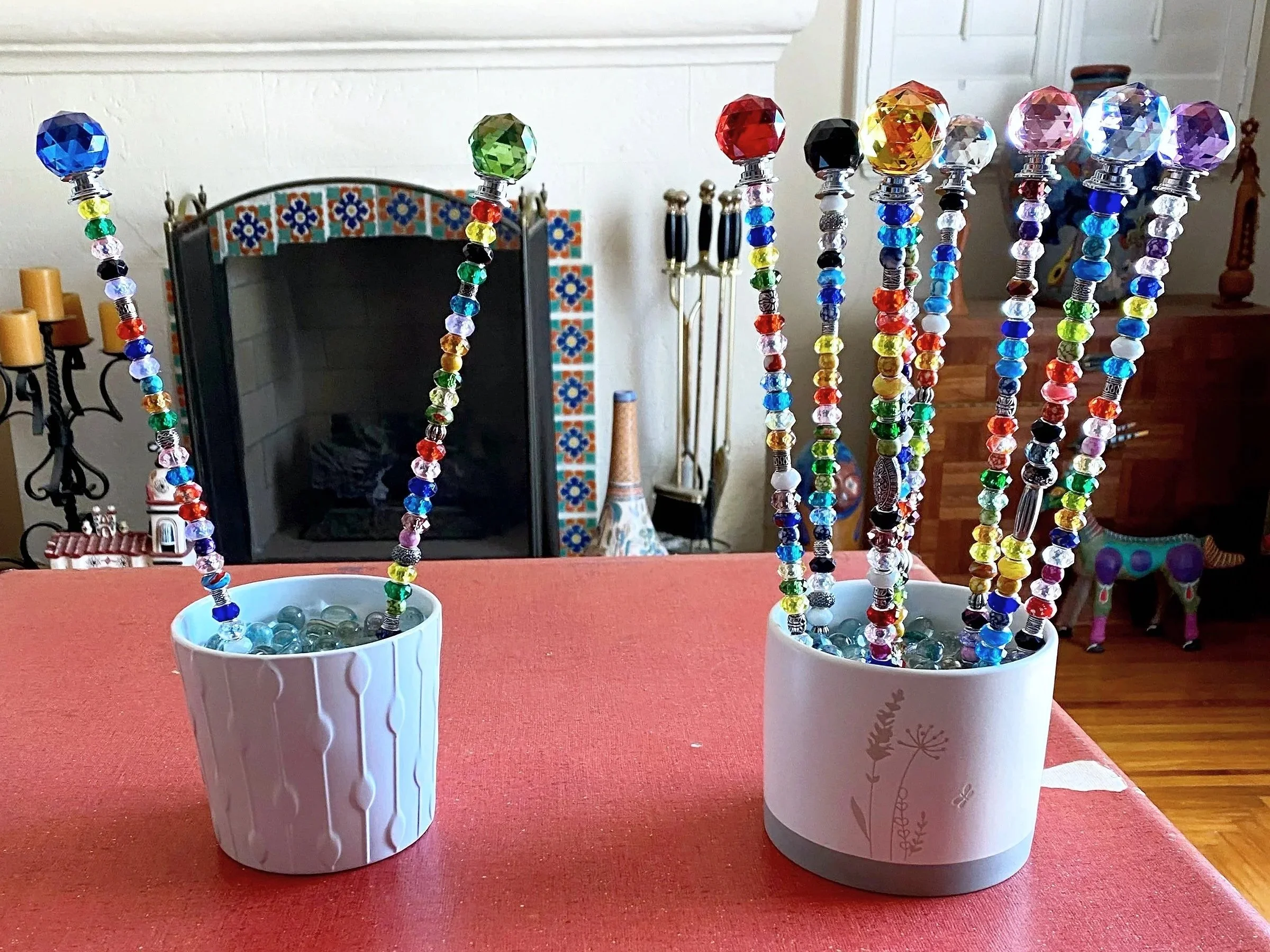 Colorful beaded jewelry necklaces displayed in white cups on a red table.