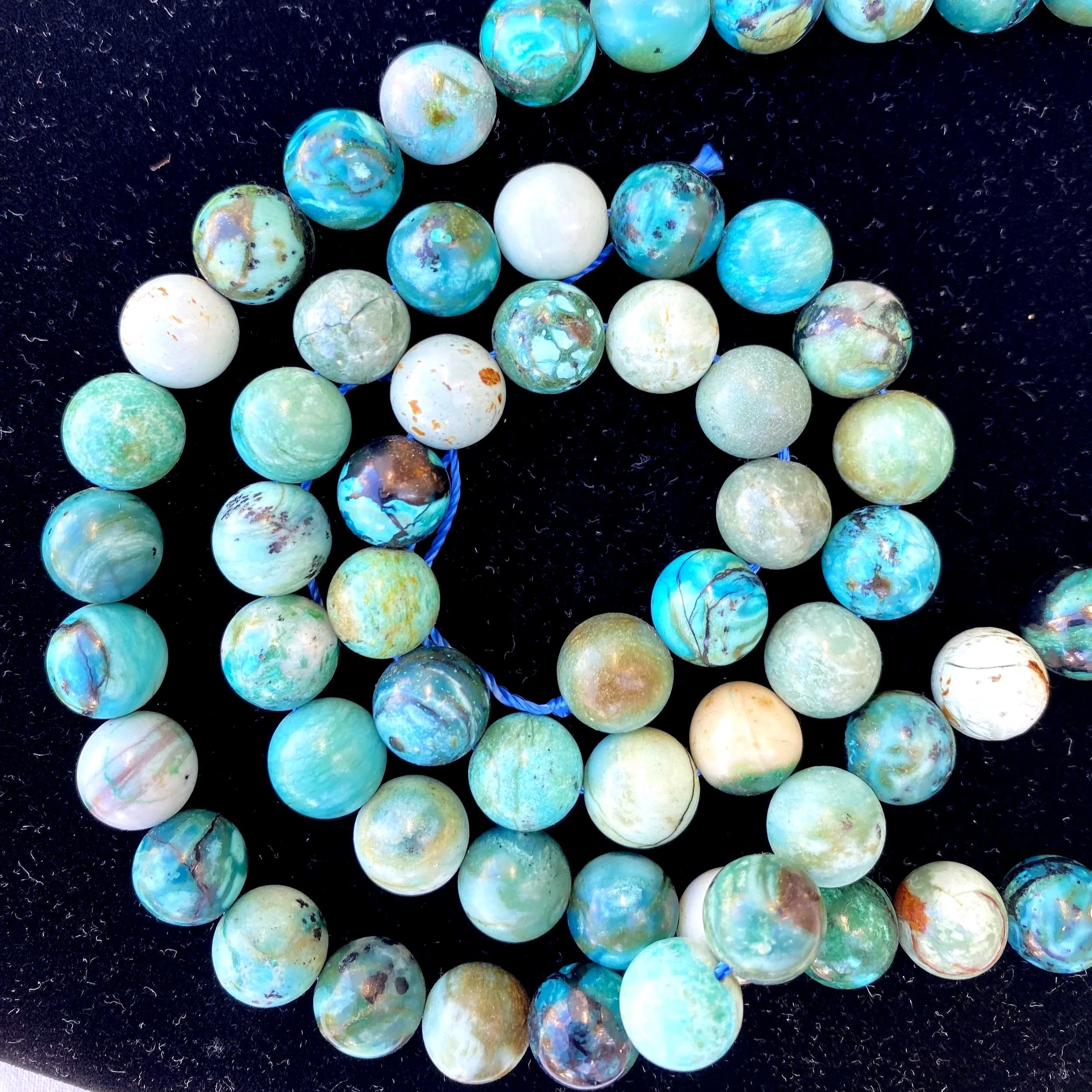 A close-up of a string of colorful marble beads on a black background.