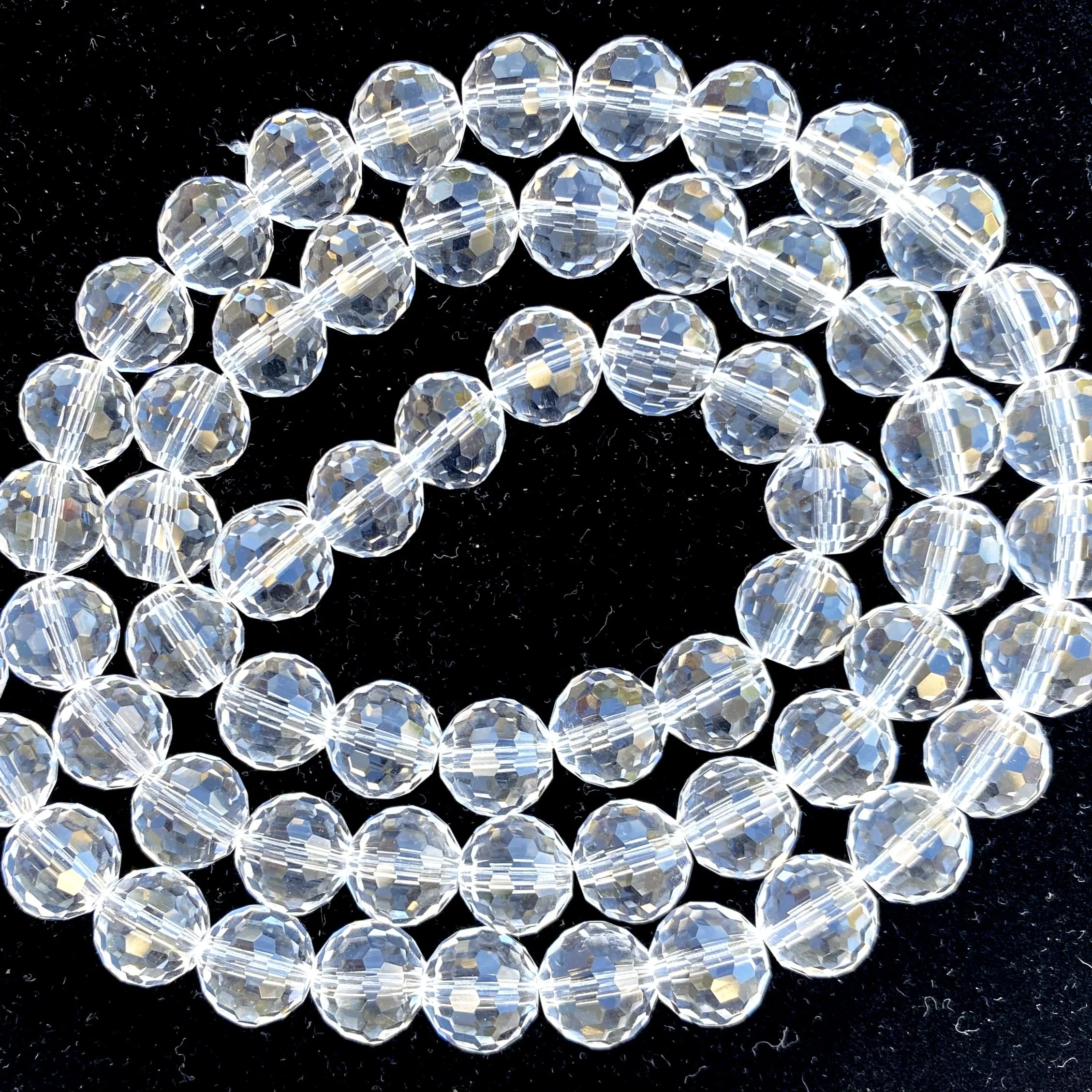 A close-up of quartz  faceted, clear, round beads set against a black background.