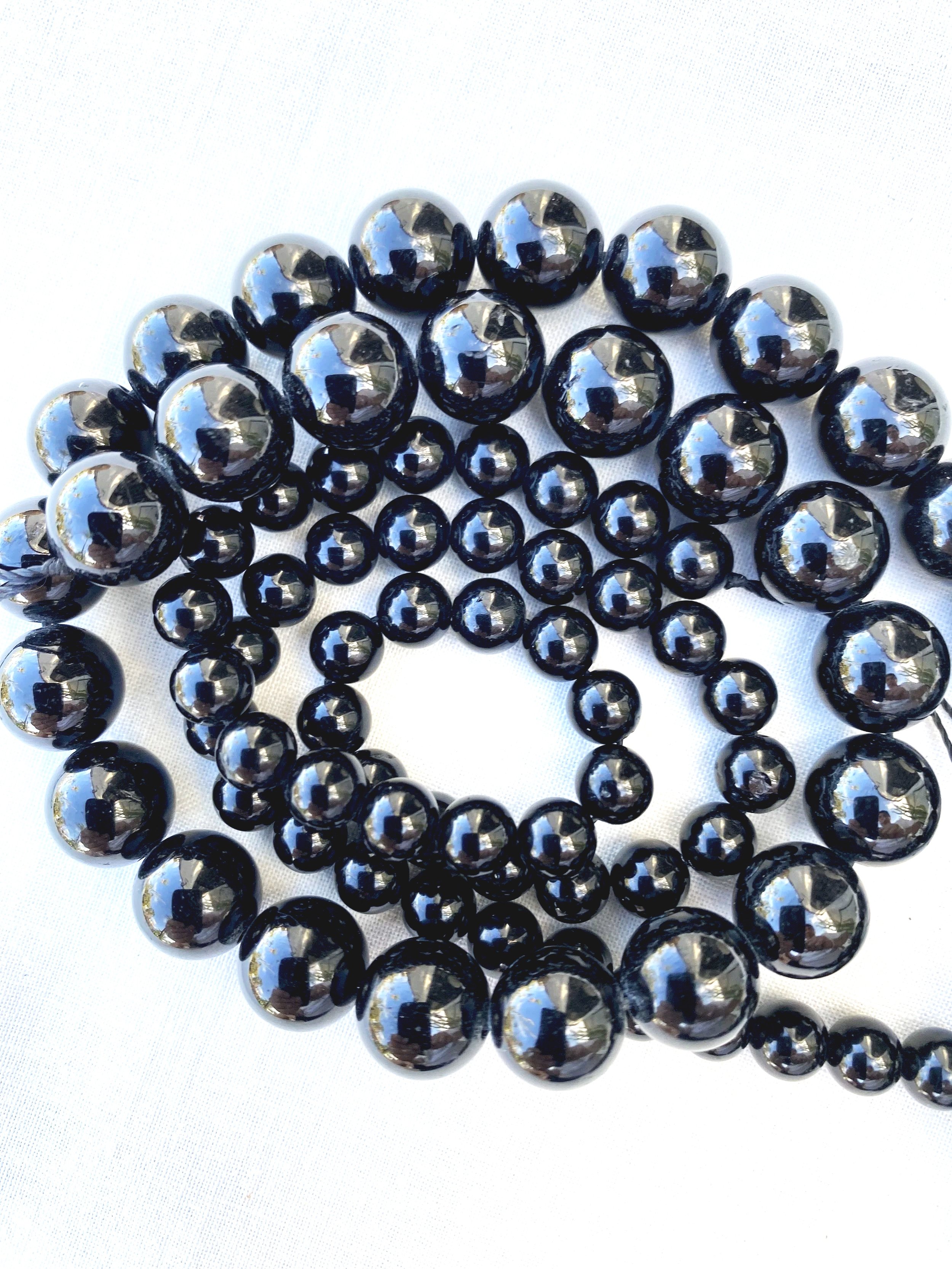 A collection of black and silver metallic beads arranged on a white surface.