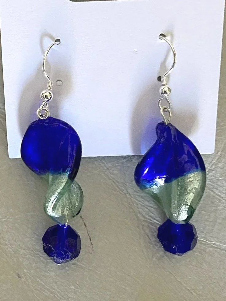 Pair of blue and green glass swirl earrings with a small blue gemstone at the bottom, hanging on a white card.