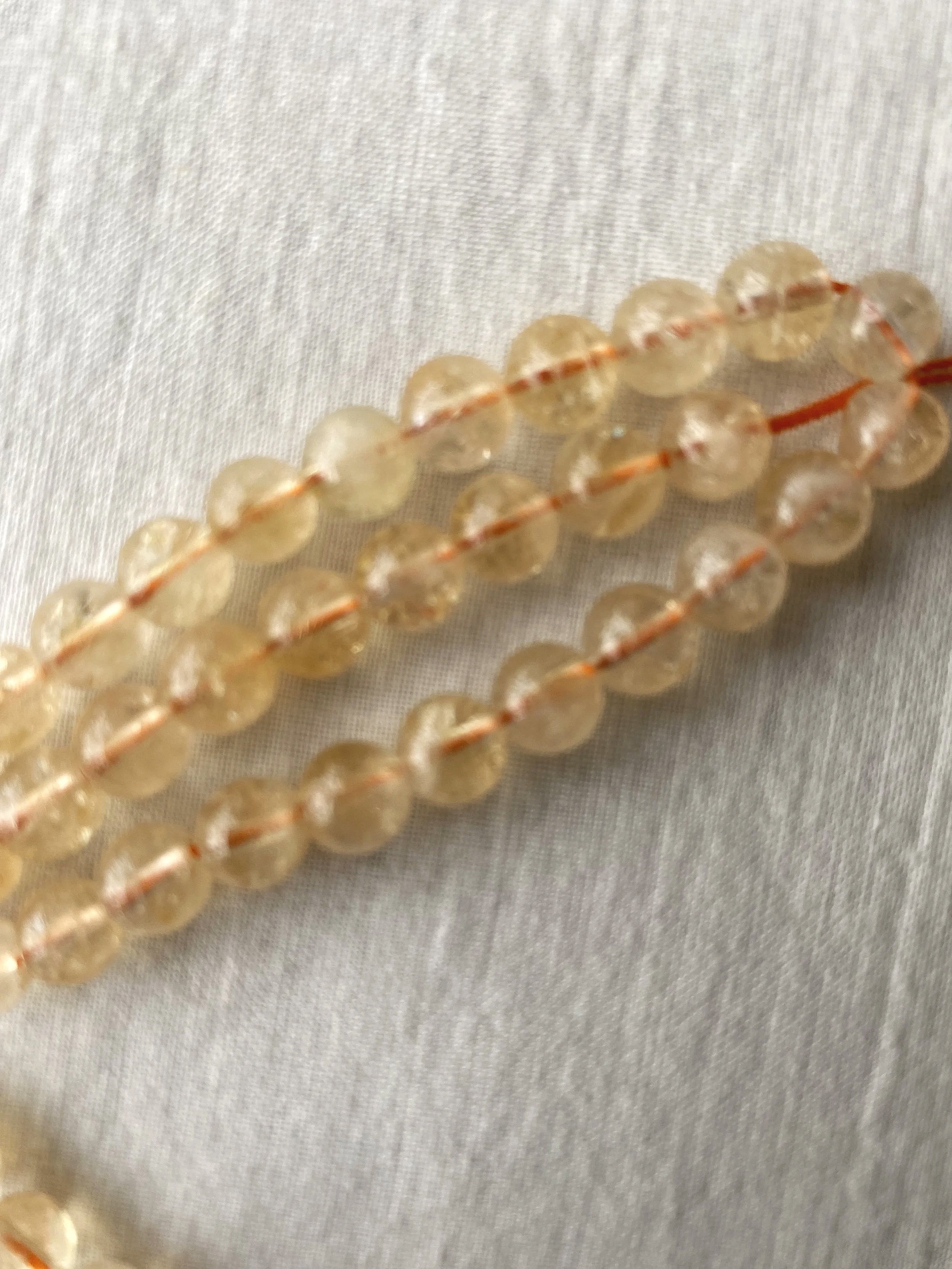 Close-up of citrine beads with a light-colored fabric background.