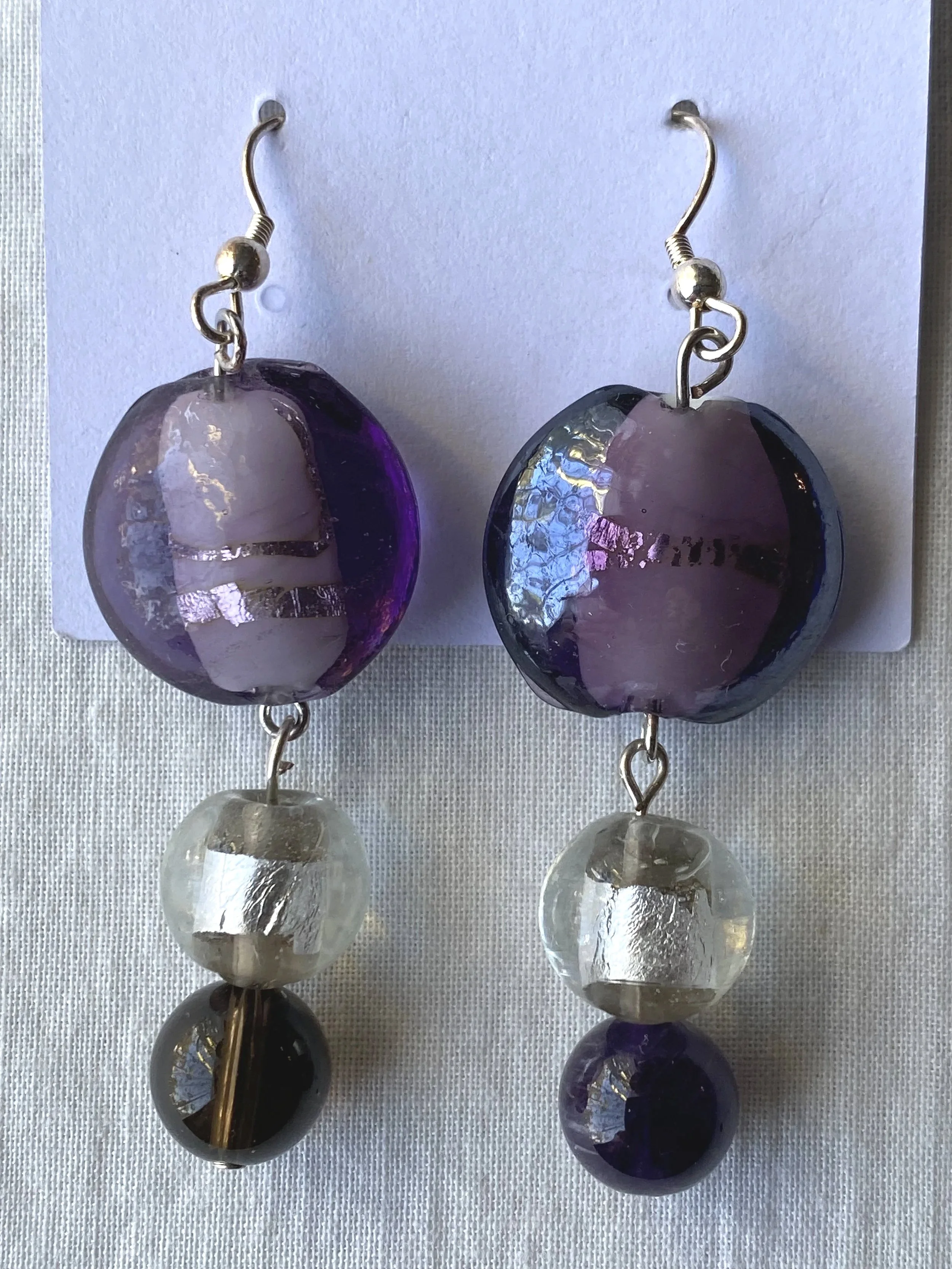 Pair of dangle earrings with purple, clear, and black beads hanging from silver hooks.