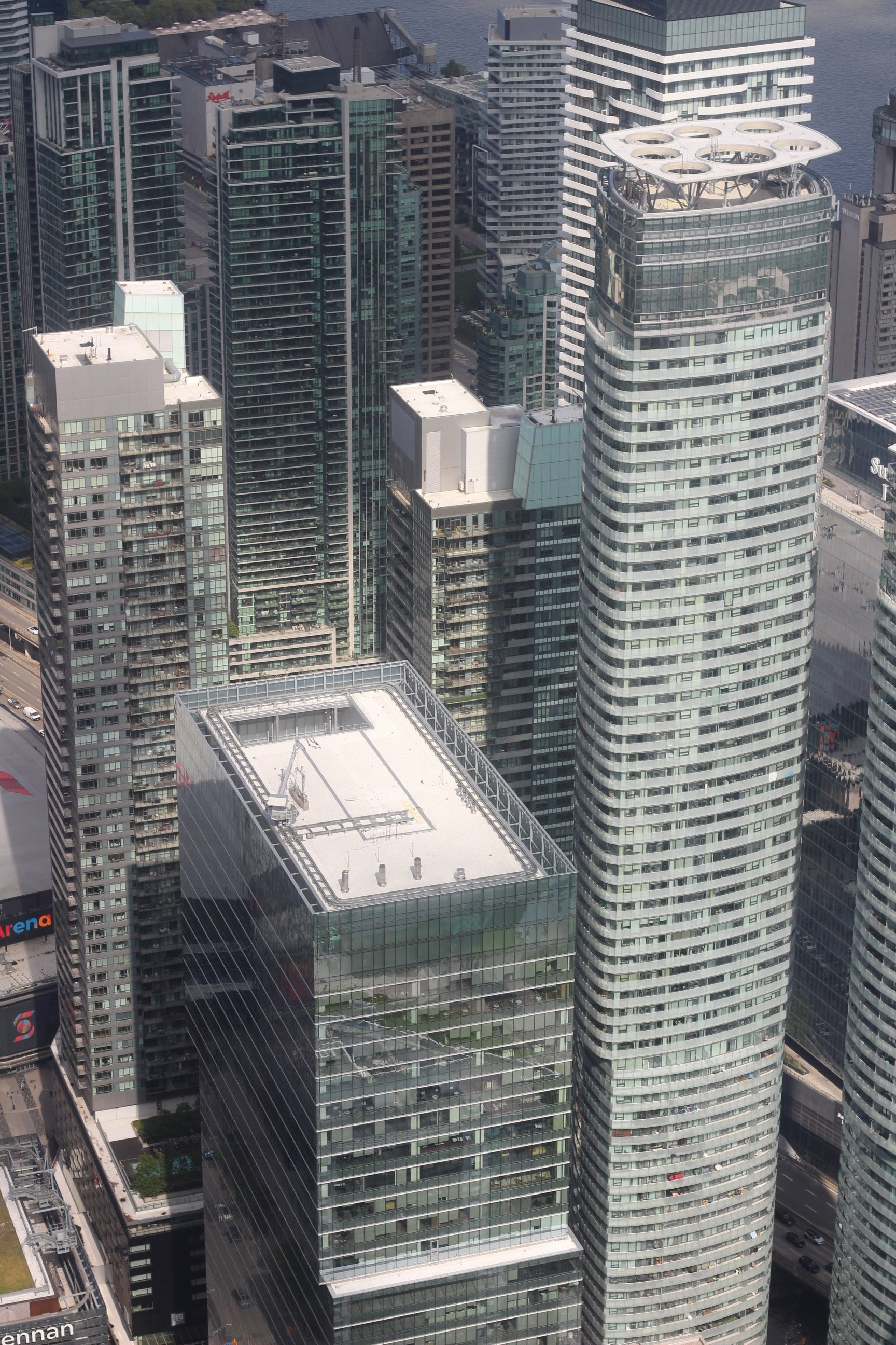 Aerial view of modern high-rise buildings in a city, with glass windows and unique architectural designs, including a building with a circular rooftop structure.