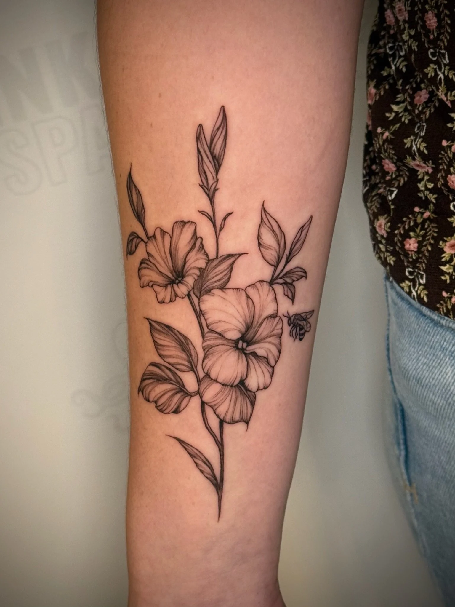 A tattoo of flowers and leaves on a person's forearm.