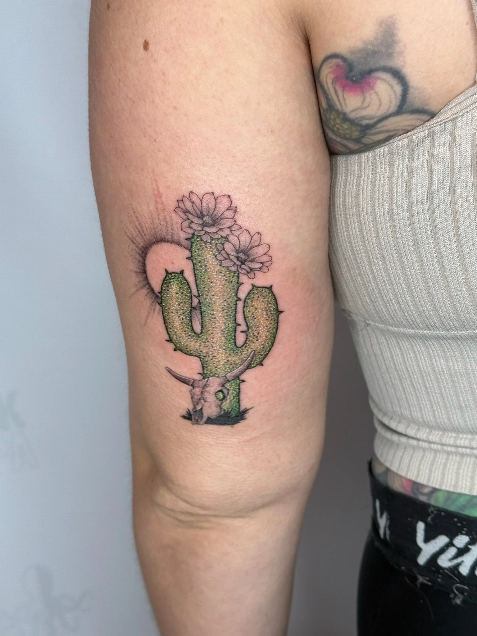 Colorful cactus flower tattoo on person's upper arm.