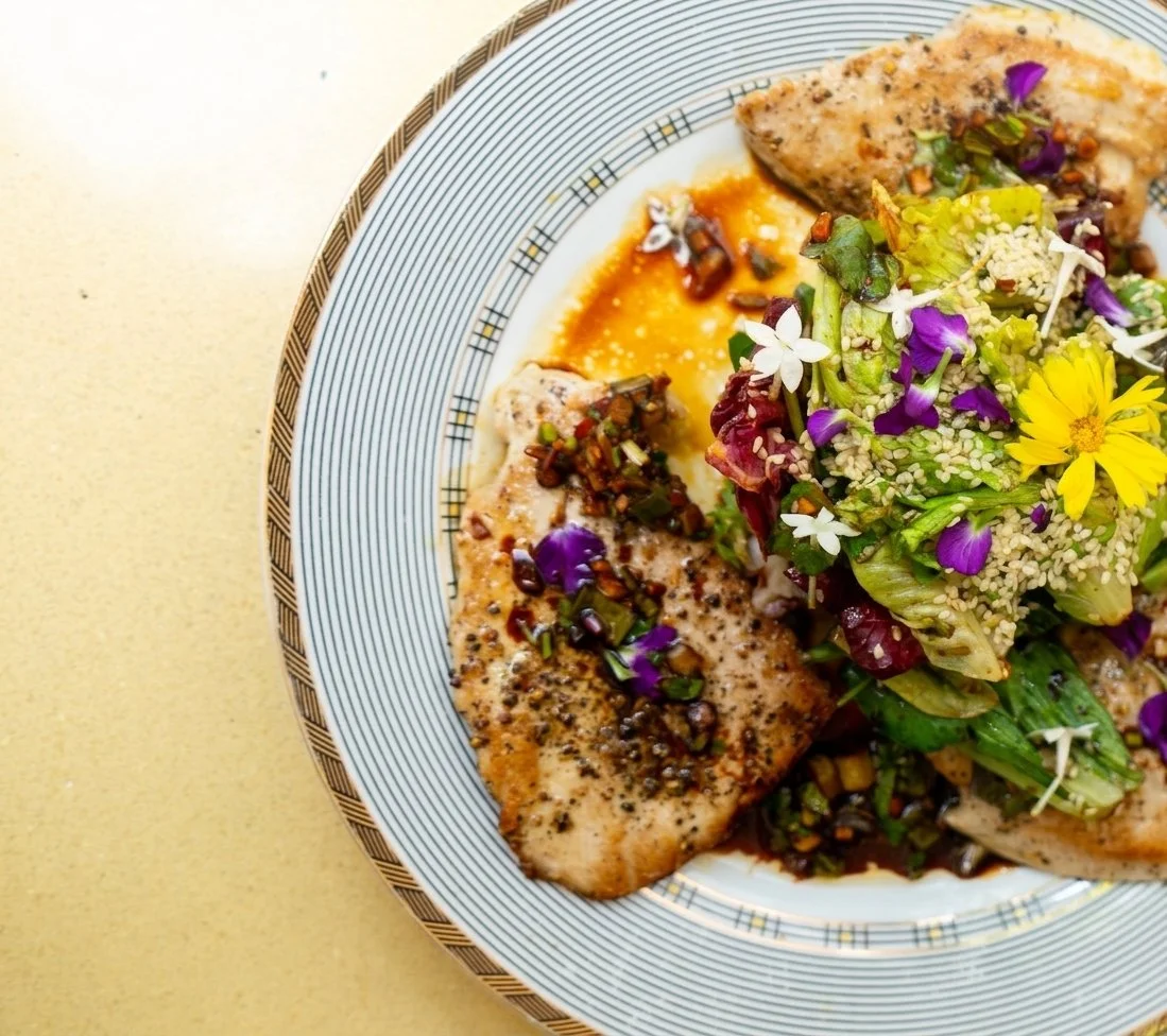 Plato de ensalada con pollo a la plancha, verduras, semillas y flores comestibles