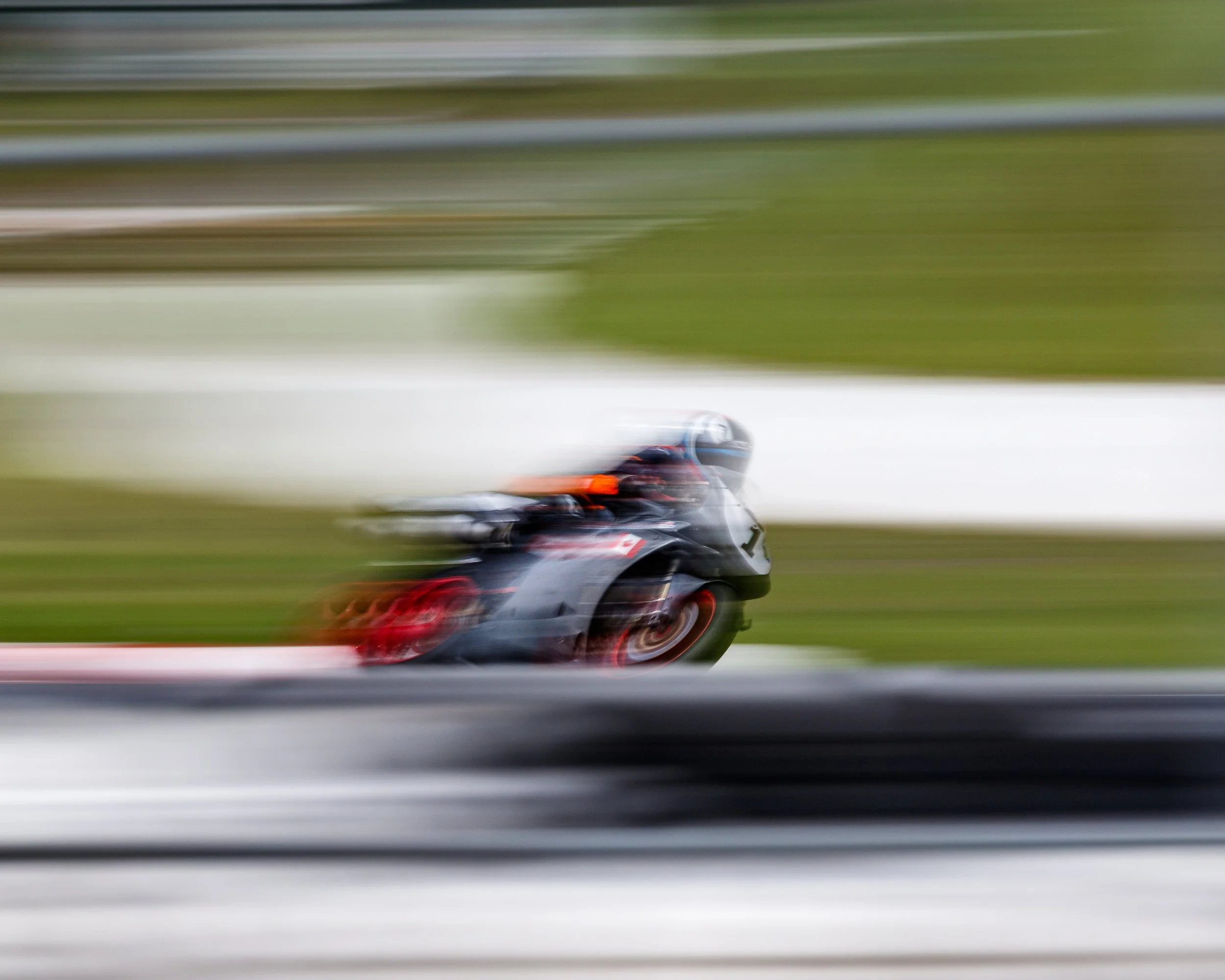 A blurred image of a race car speeding on a track, with motion lines indicating high speed.