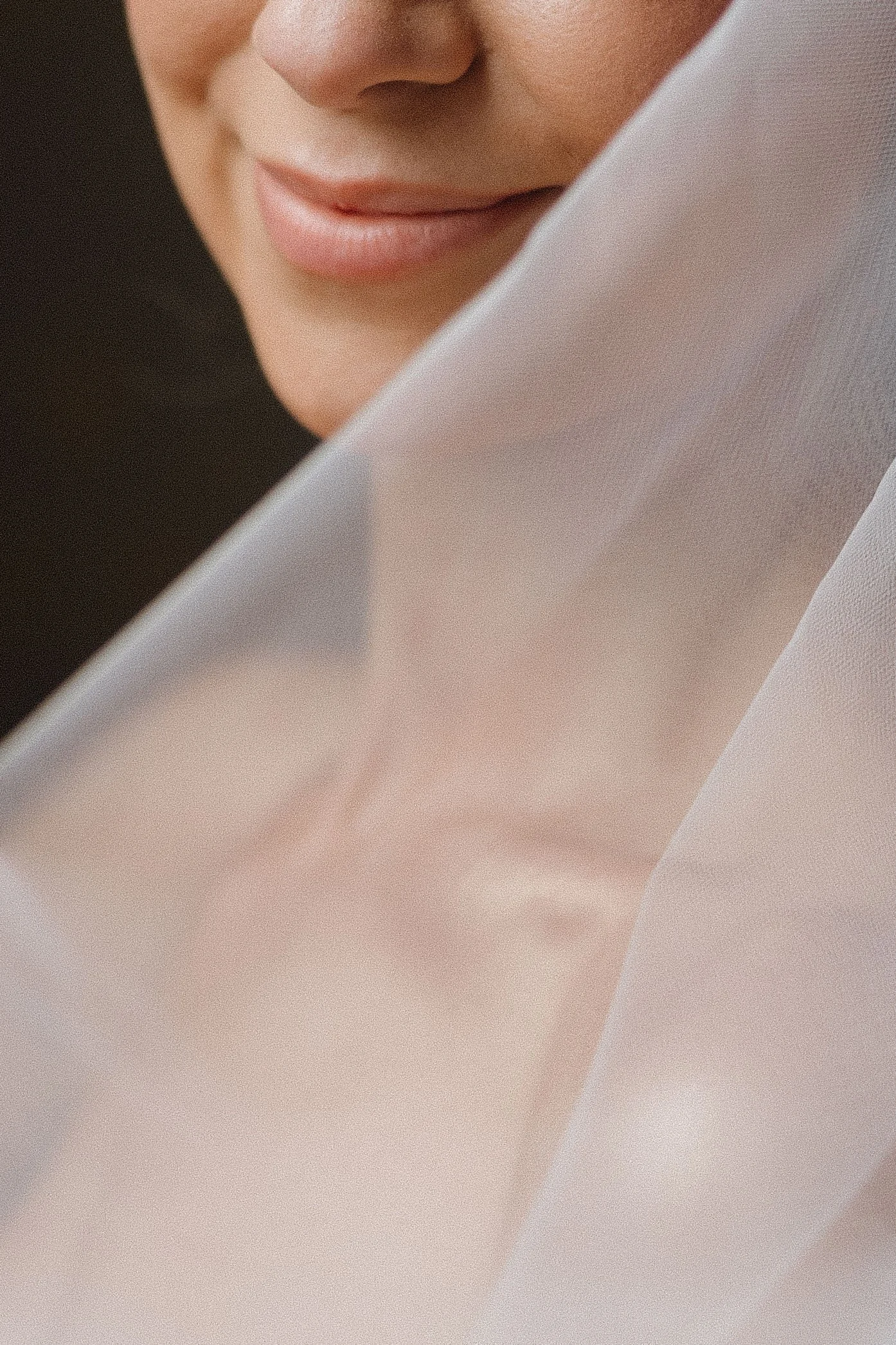 Close-up of a person's mouth, nose, and part of a face, partly covered by a light pink or beige fabric or paper.