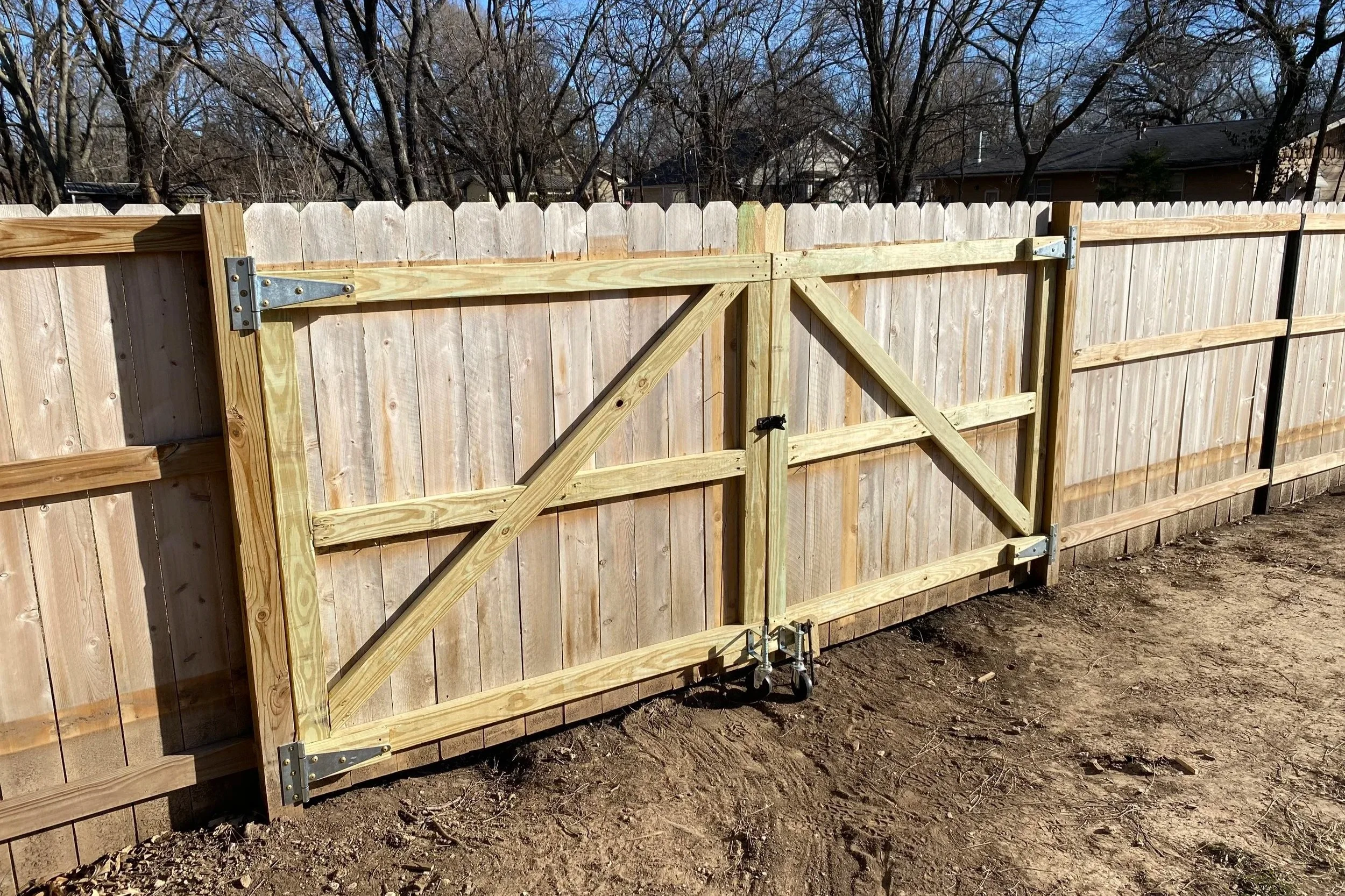 A new wooden fence with a gate under construction in a residential backyard.