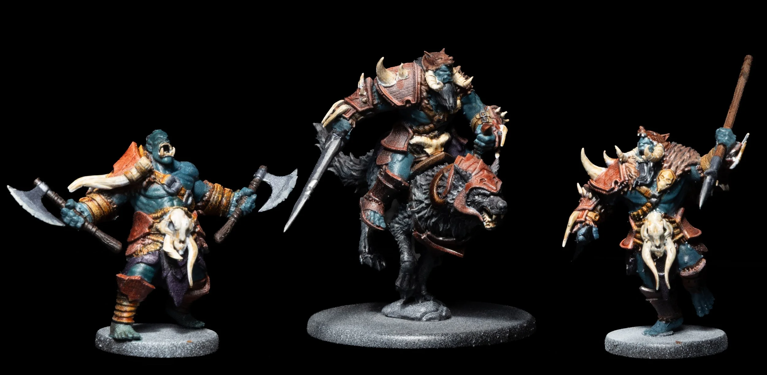 Miniature fantasy warriors with blue skin, wearing armor with skull and bone motifs, wielding weapons, riding a mounted beast, against a black background.
