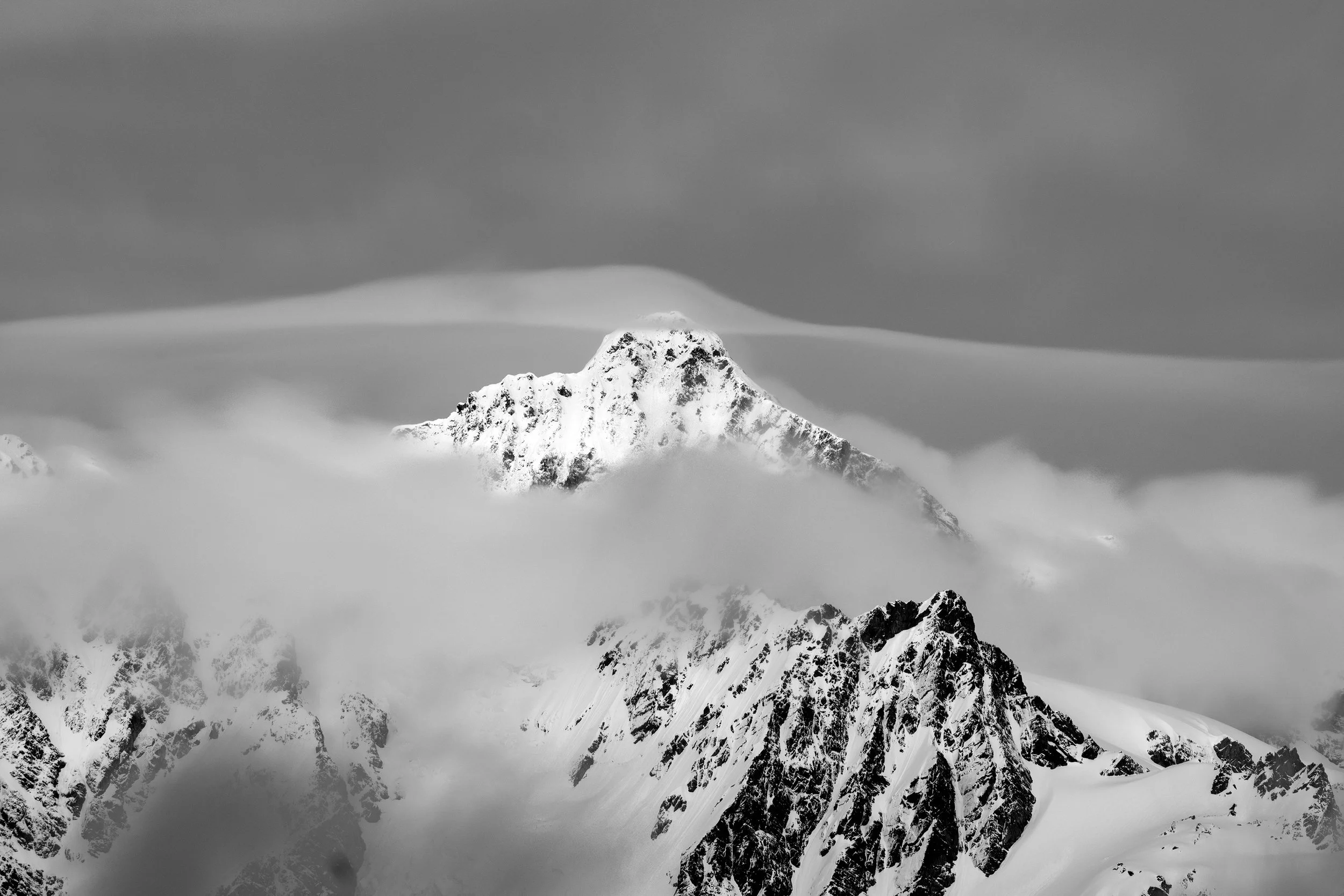 Snow-covered mountain peak surrounded by clouds.