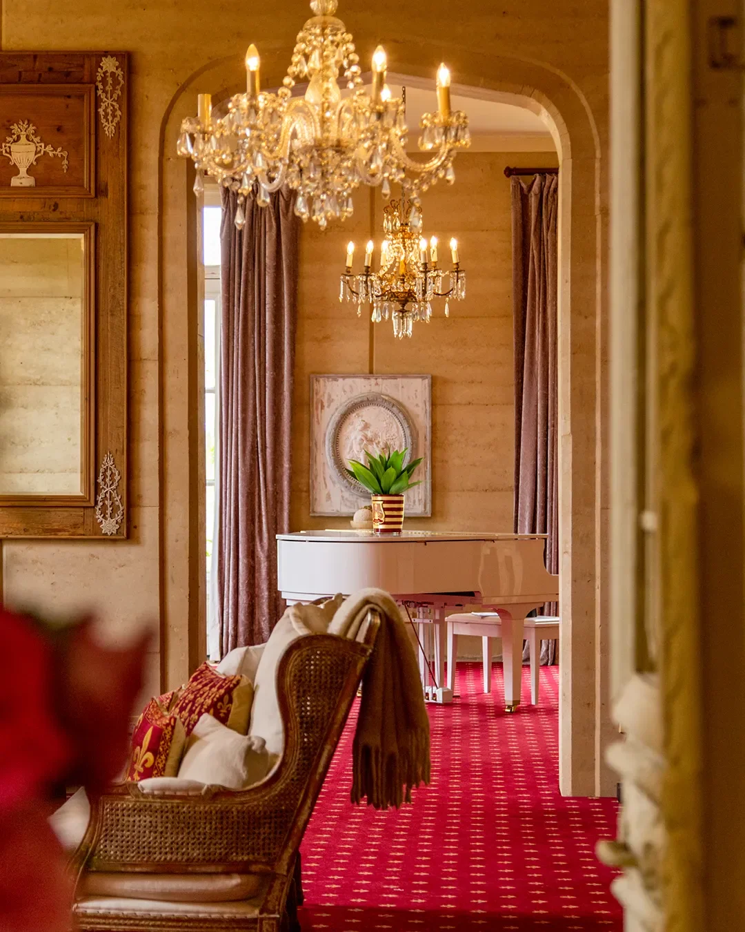 Elegant interior with chandeliers, a white grand piano, and warm-toned decor.