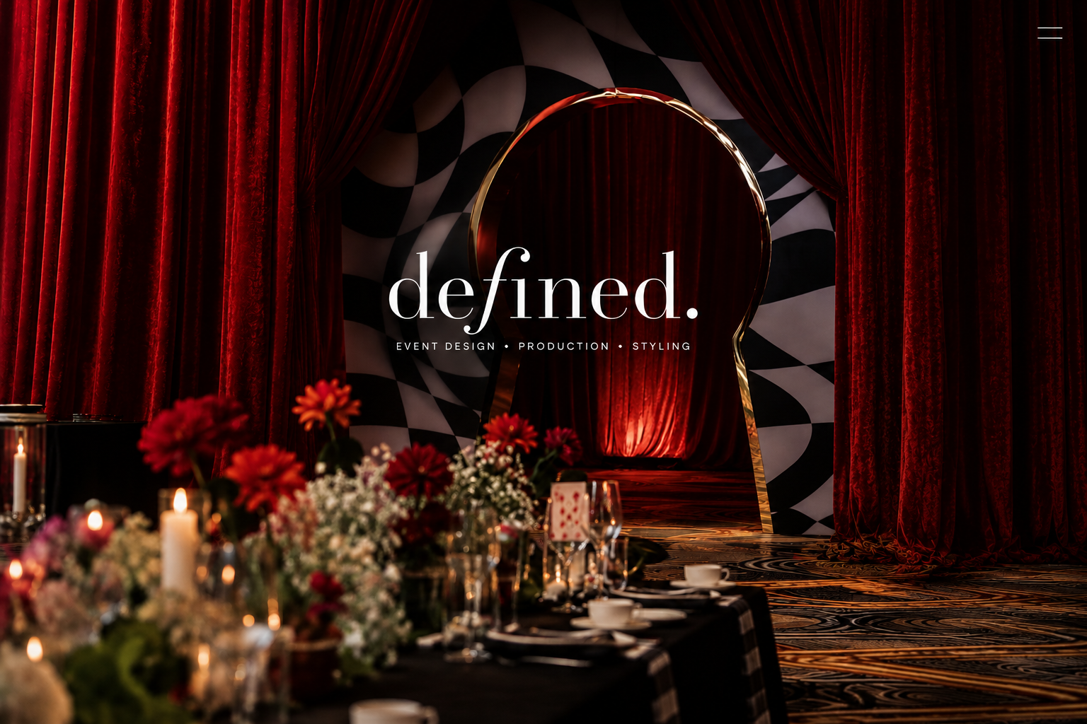 Elegant event styling featuring rich red velvet draping, floral centrepieces, candlelit tables and a dramatic backdrop by Defined in Melbourne.