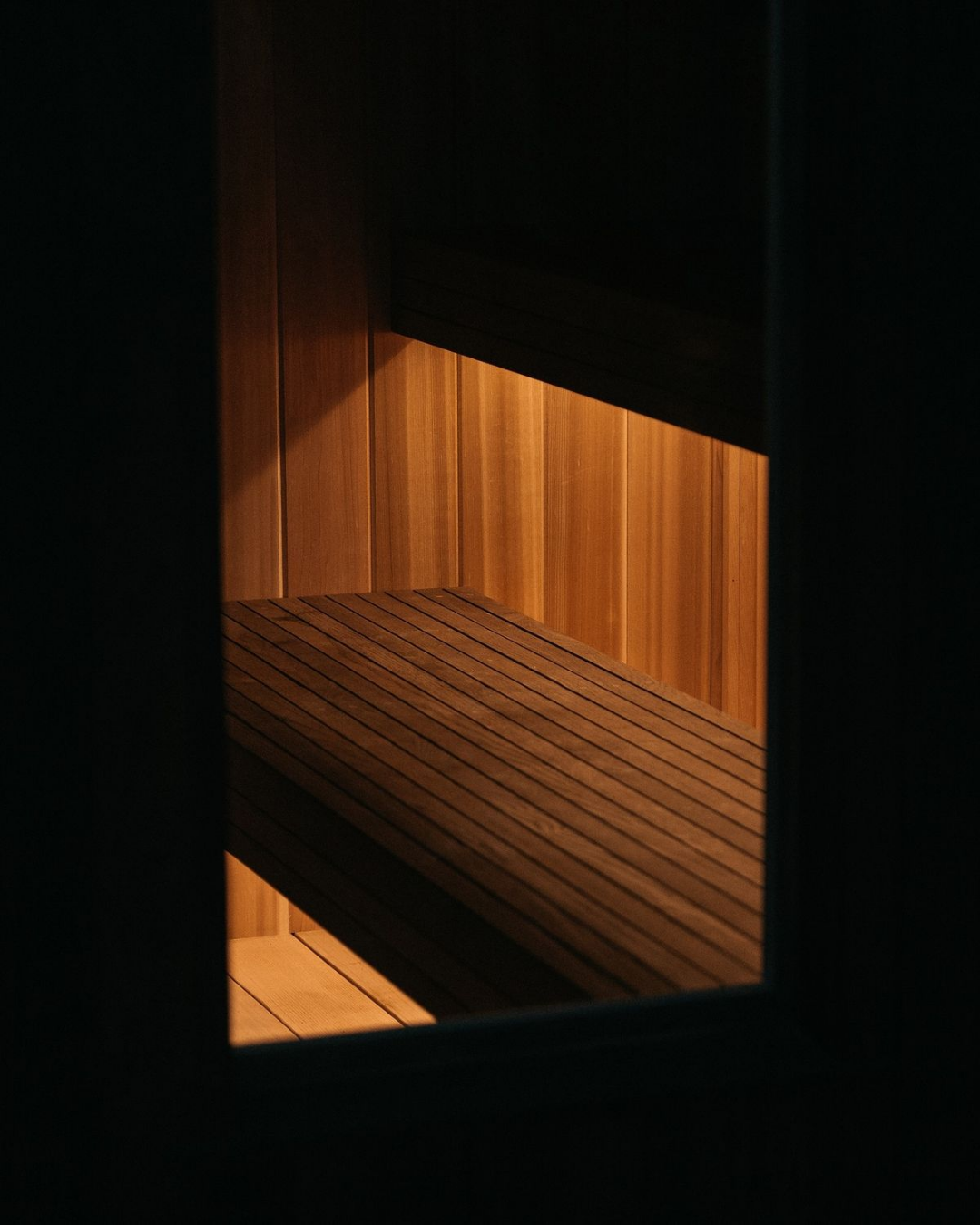 Wooden sauna interior with horizontal and vertical slats, dim lighting