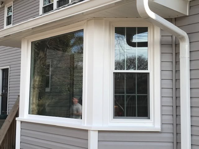 The exterior of a house with vinyl siding and a large bay window with three panes.