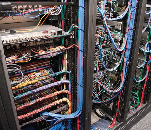 Inside a server room with network and power cables organized in black racks.