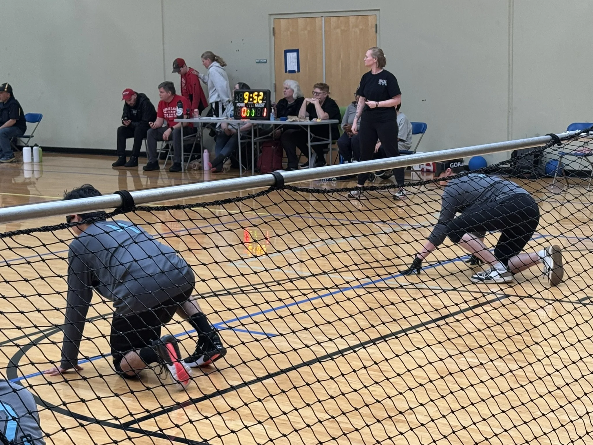 Photo of two SD Goalball players taken from behind the net as they are in their defense crouch waiting for the opponent's goalball delivery.