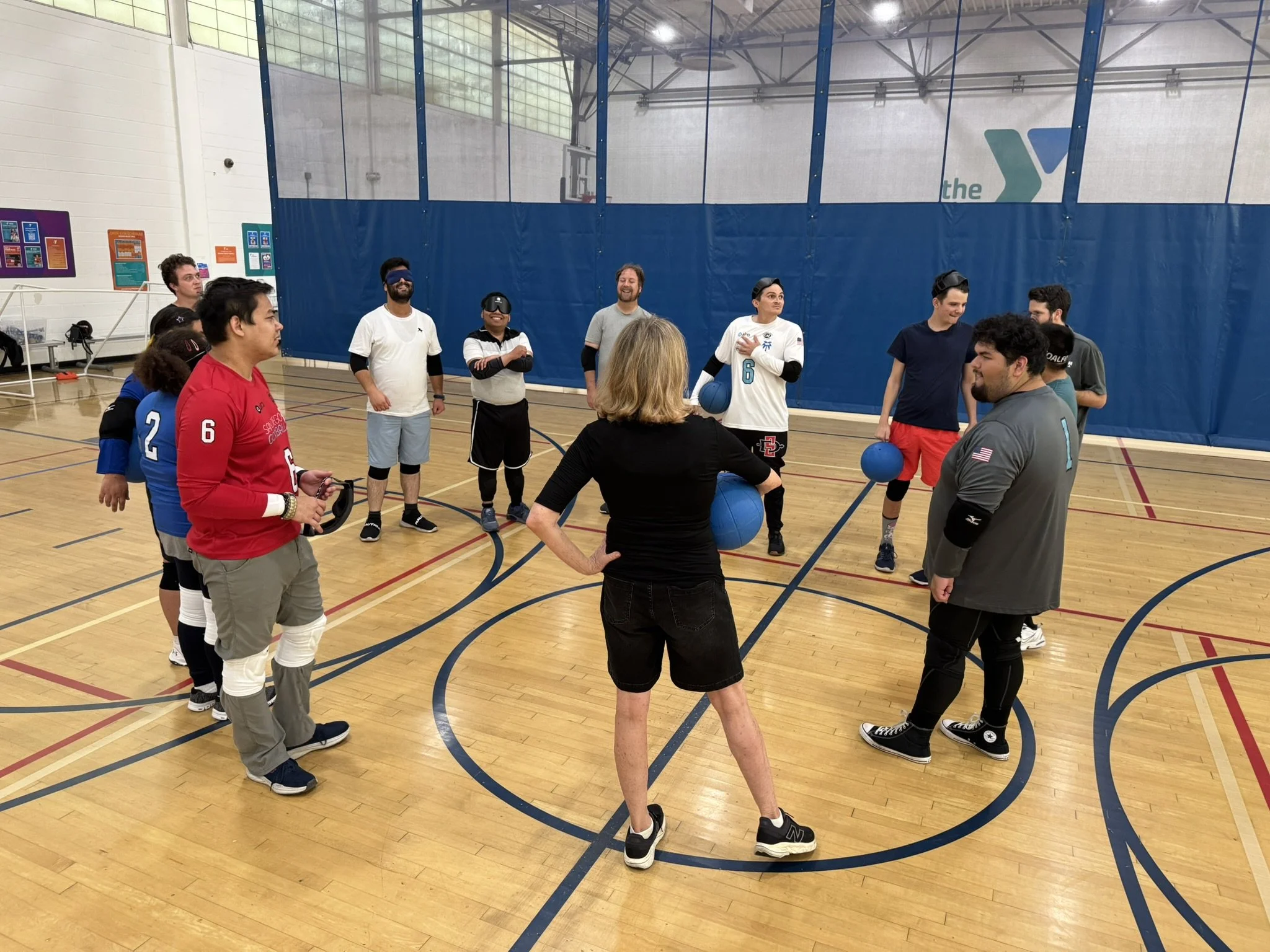 The goalball team circles up at a practice to discuss strategy at the Mission Valley YMCA during practice