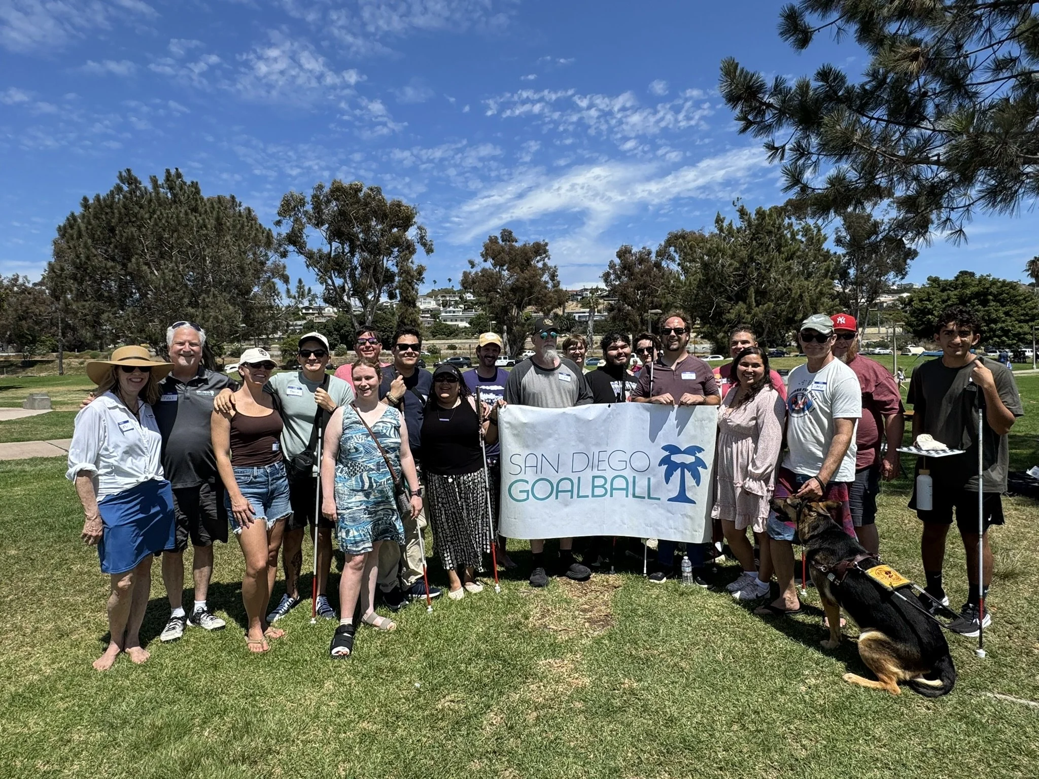 San Diego Goalball team holding the San Diego Goalball team and supporters in a park with blue skies.