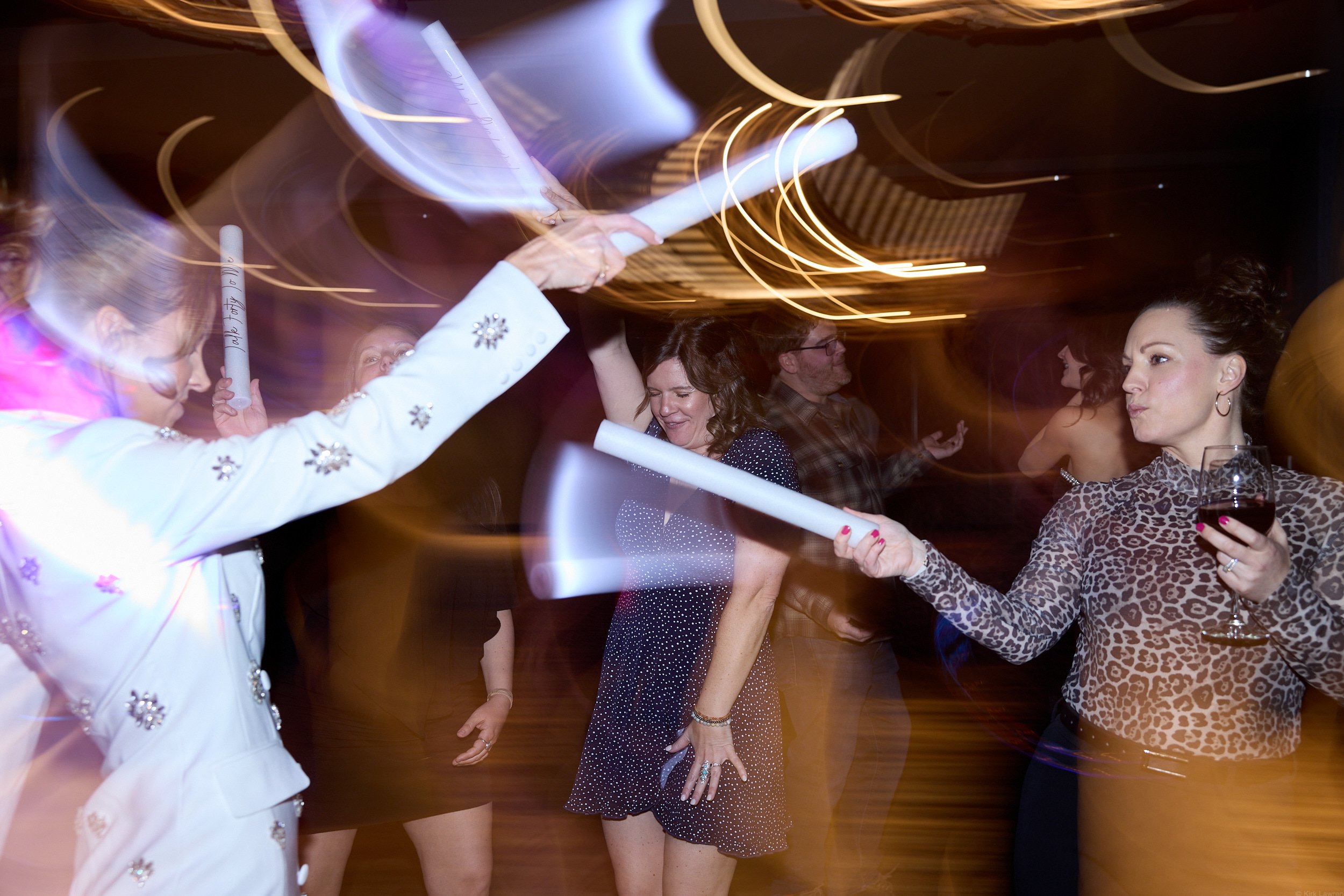 People dancing at a party in a dimly lit room with motion blur, with swirling lights in the background.