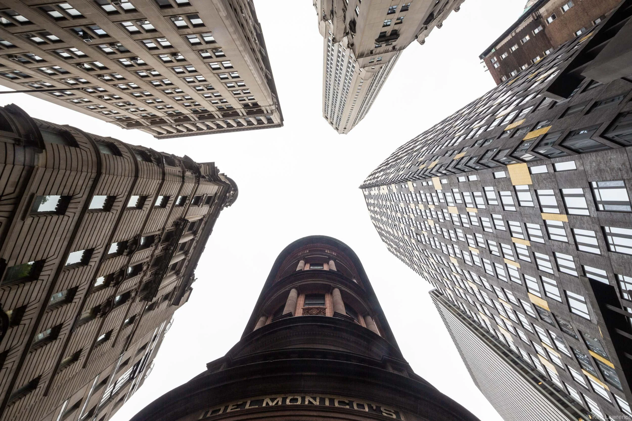 Looking up at tall skyscrapers with a partly cloudy sky above.