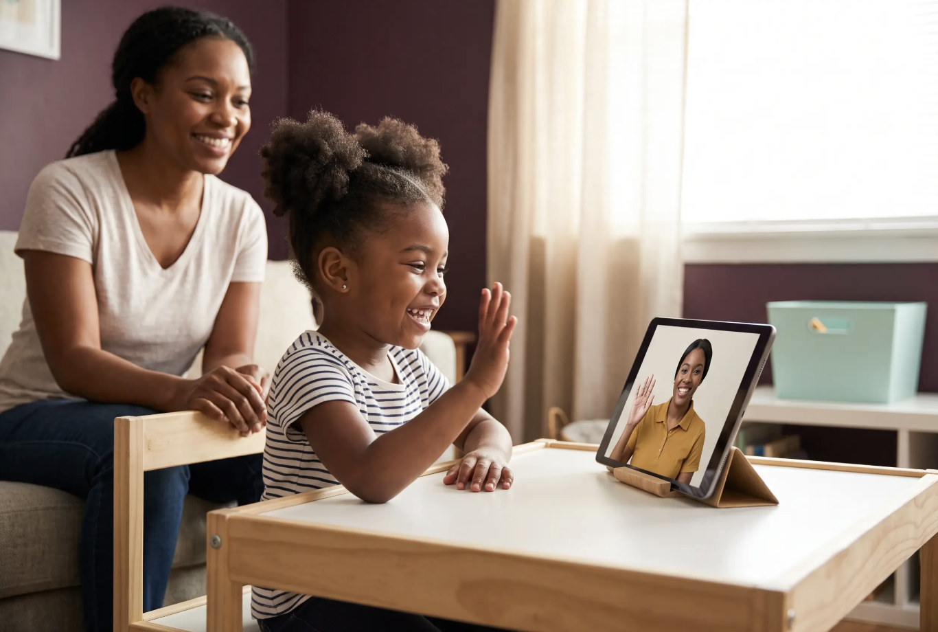 A woman and a young girl attending a video call on a tablet, with the girl waving at the person on the screen. The woman is smiling and sitting beside the girl in a cozy room with natural light.