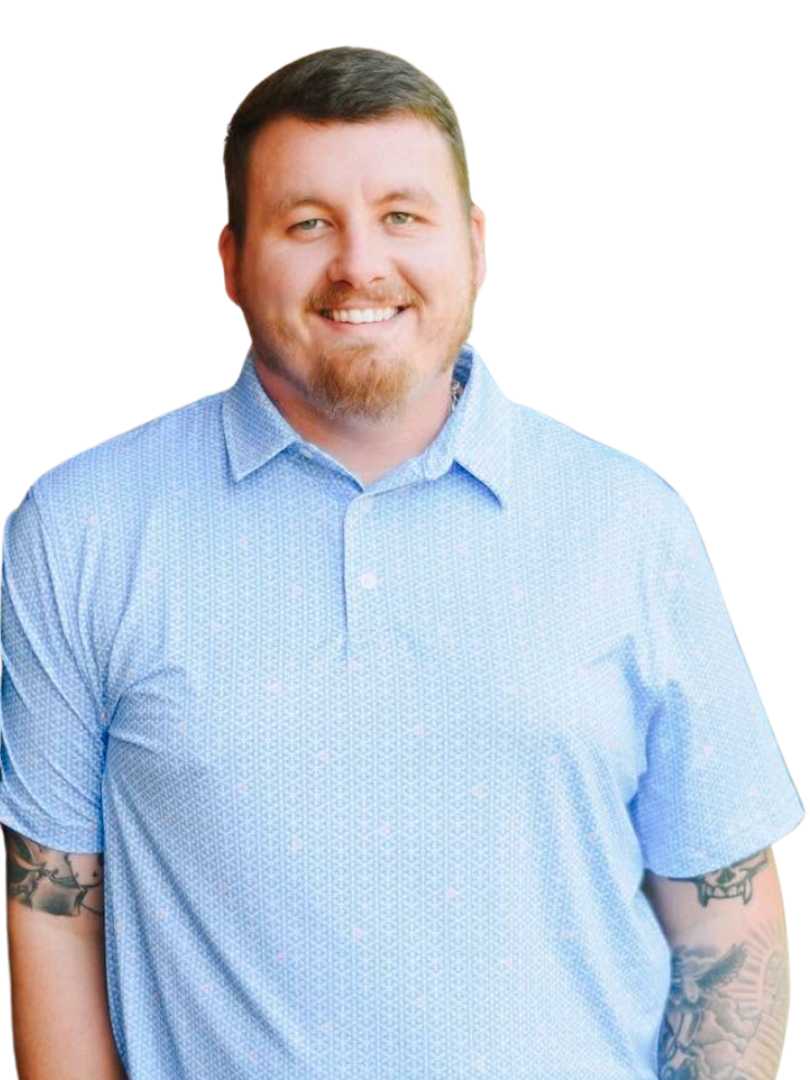 A smiling man with short brown hair and a beard, wearing a light blue collared shirt, standing against a plain background.