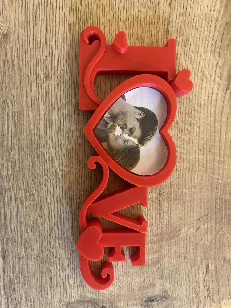 Red decorative photo frame with the word 'LOVE' and heart shapes, containing a photo of a couple kissing.