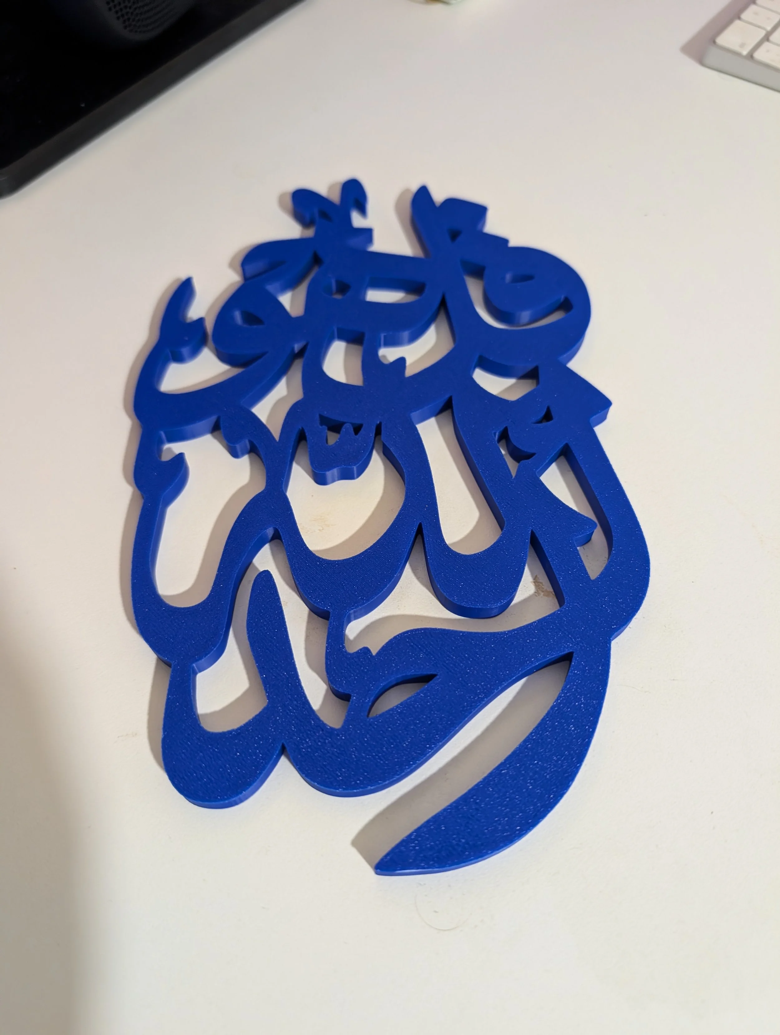 Blue plastic snowflake-shaped decoration on a white surface with part of a keyboard visible in the background.