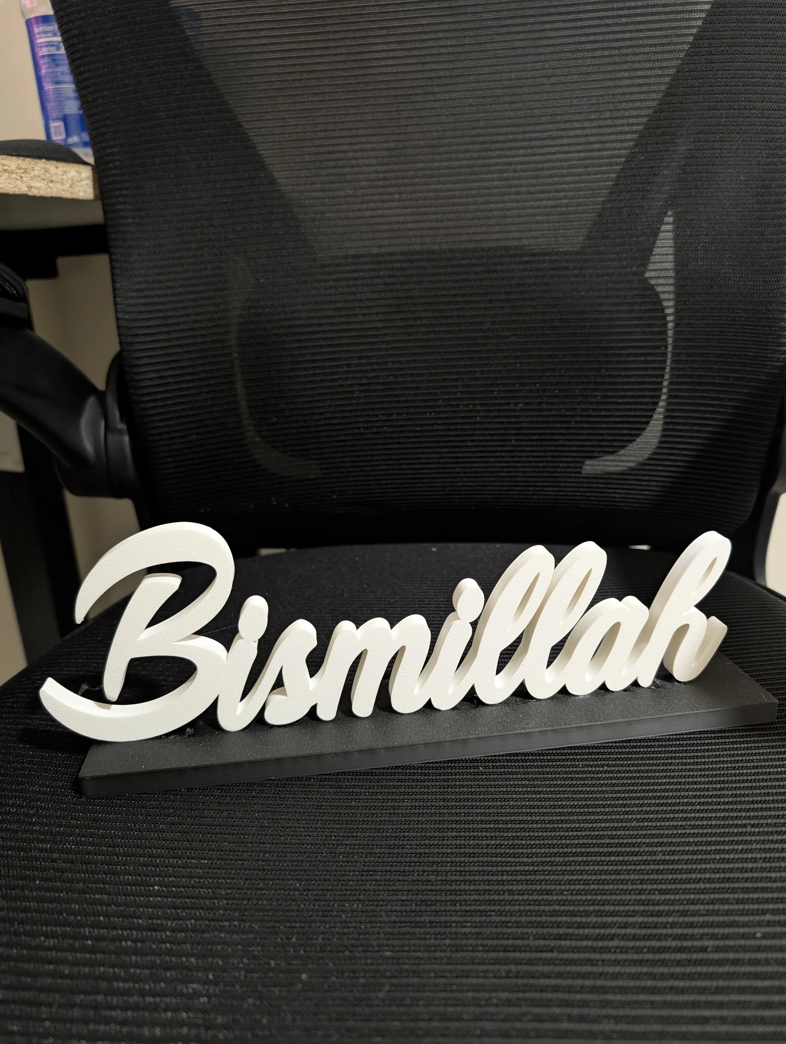 White cursive 'Birmingham' sign on black base placed on a black textured surface.