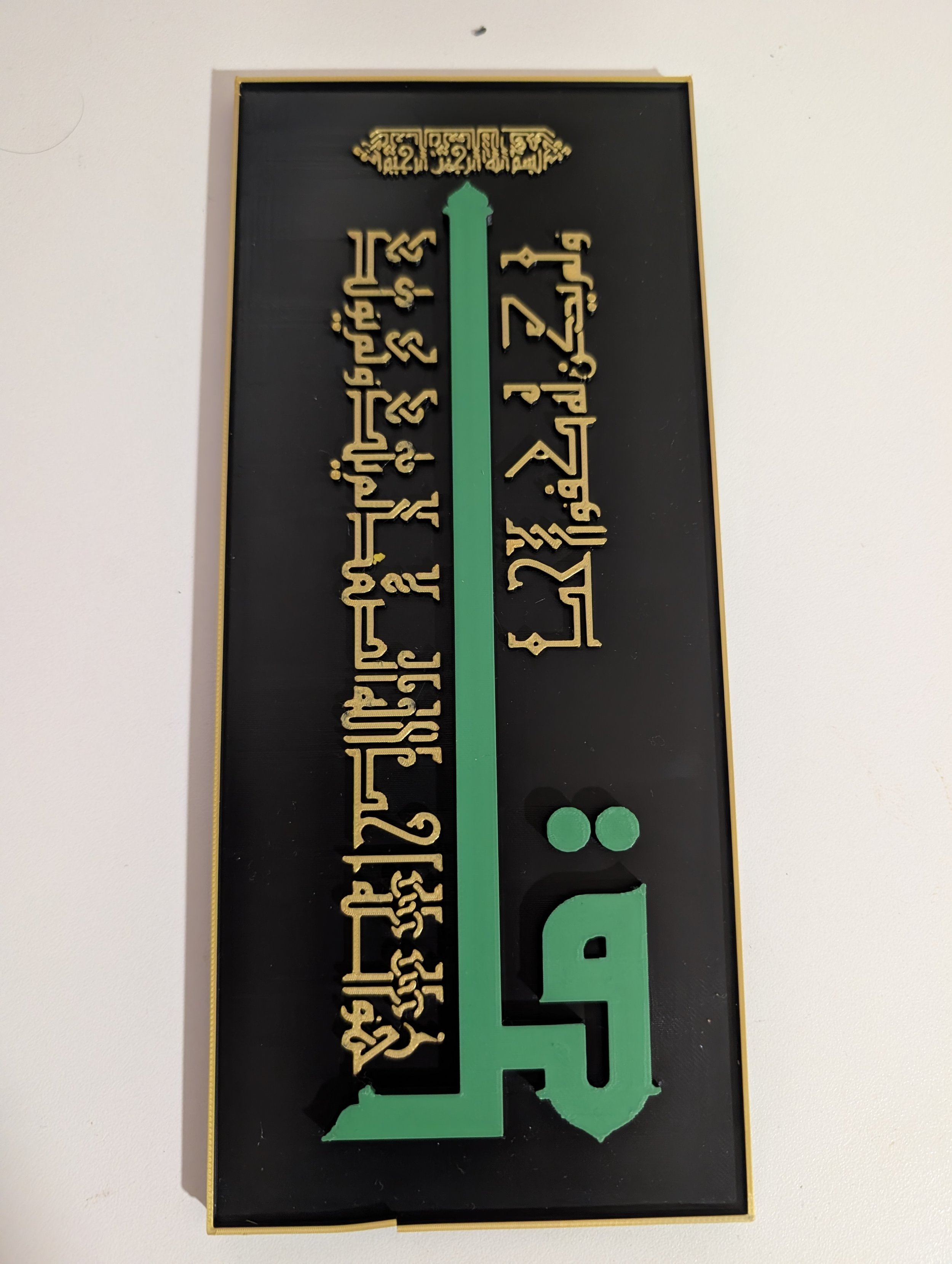 A black display board with gold and green elements, featuring Arabic calligraphy at the top, a large green number two in the center, and a large green number five at the bottom.