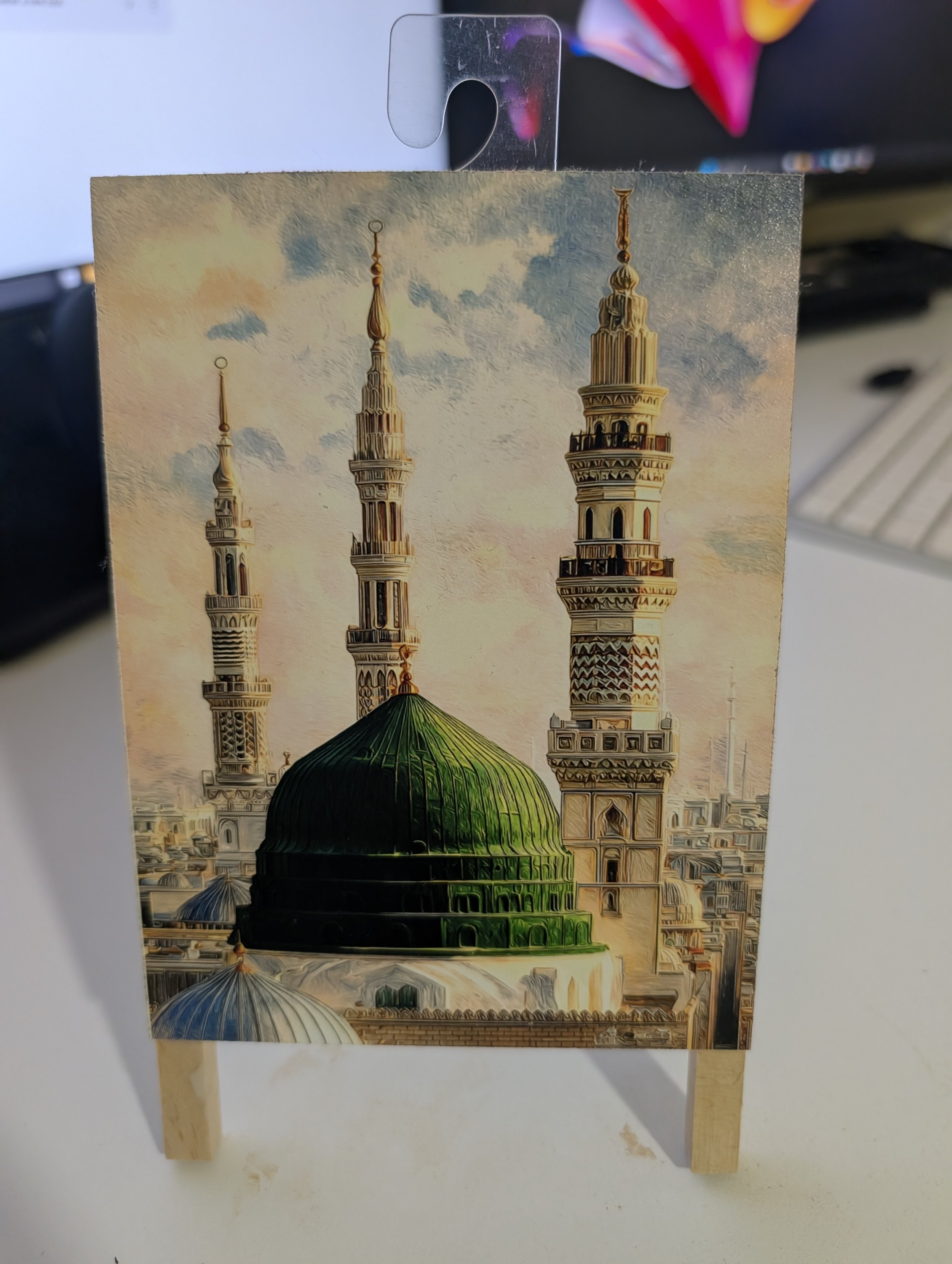 Painting of a Middle Eastern mosque with three minarets and a green dome against a sky with clouds.