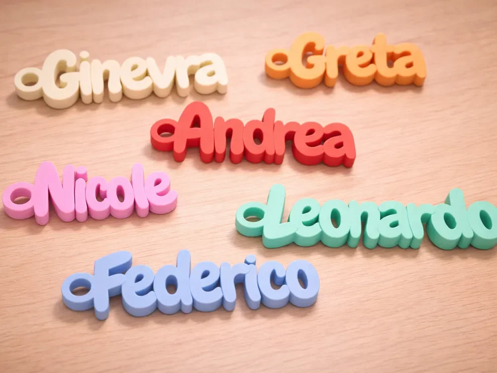 Colorful 3D words of five names arranged on a wooden surface: Ginevra, Greta, Andrea, Nicole, Leonardo, Federico.