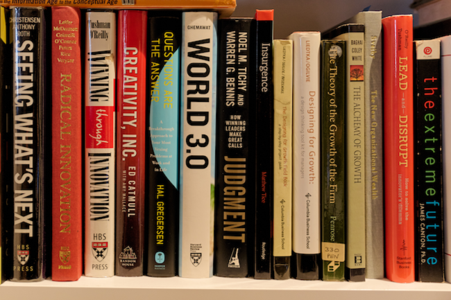 A bookshelf filled with various books including 'Thinking What’s Next,' 'Radical Innovation,' 'Creative Incubation,' 'Questions Are the Answer,' 'World 3.0,' 'Judgment,' and 'The Next Future.'