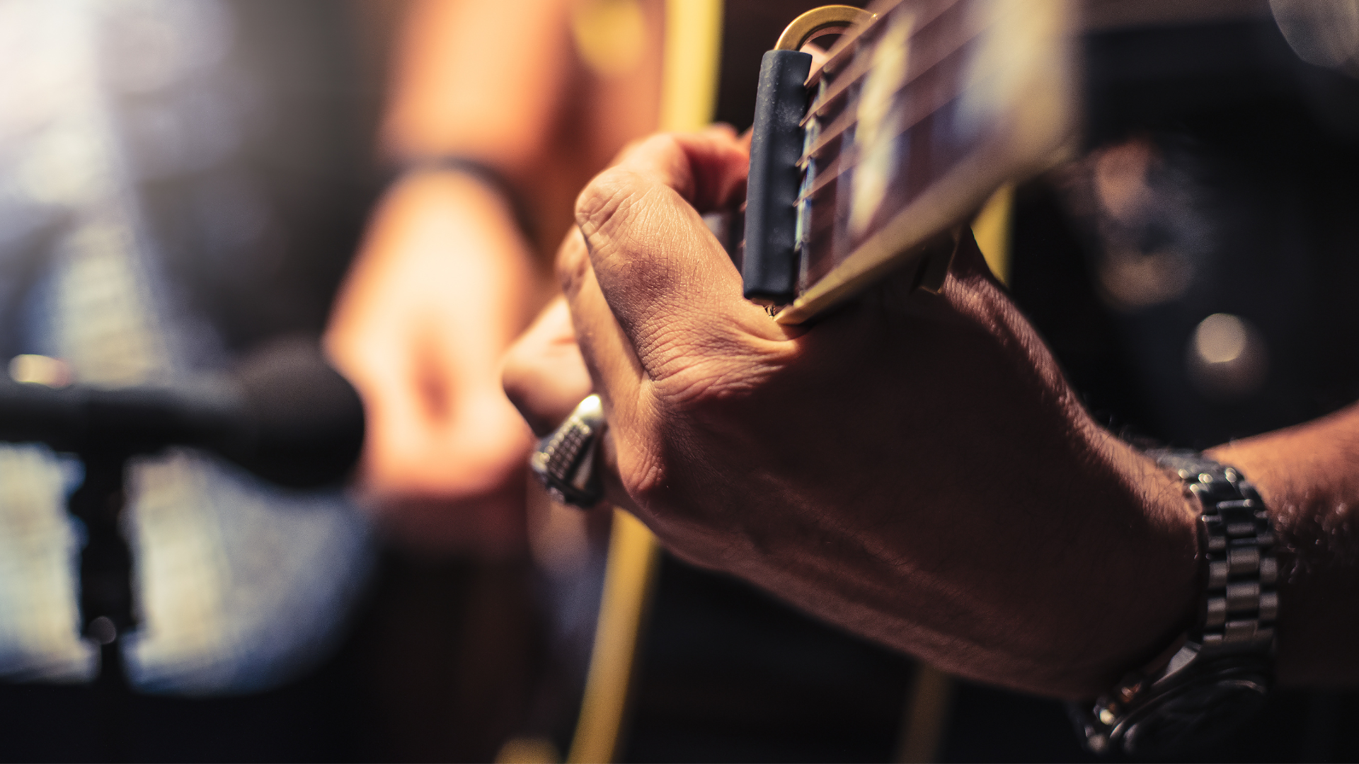 A person holding a guitar with a microphone nearby