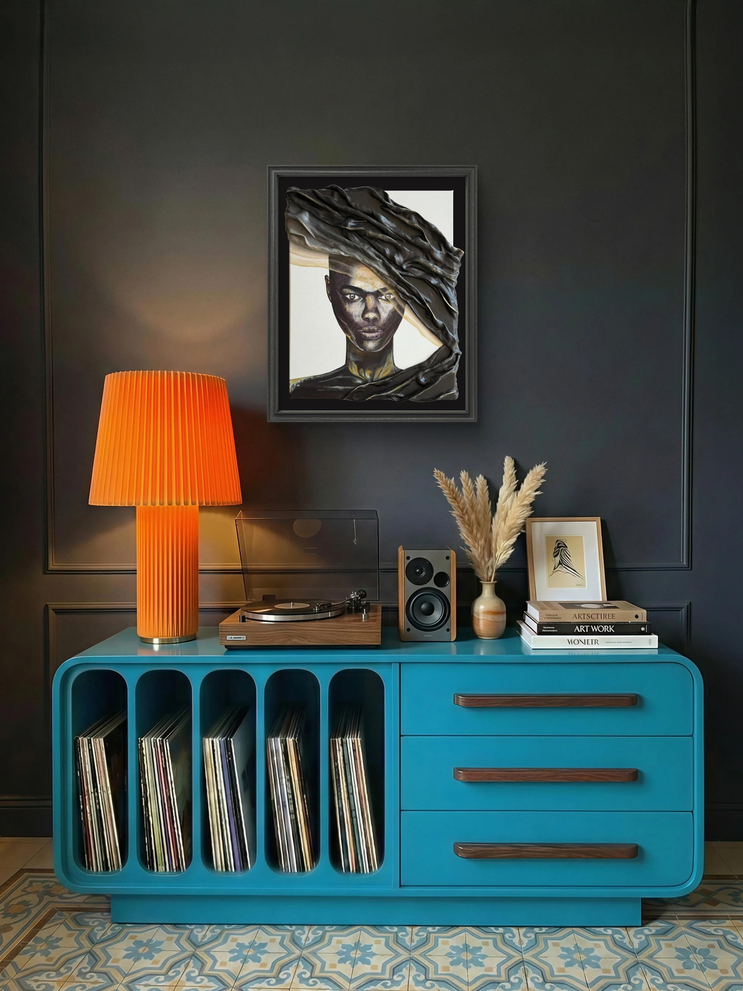 A vintage-style room corner with a bright blue vinyl record storage cabinet, topped with a modern wooden turntable, a beige vase with dried pampas grass, a speaker, and a framed artwork of a bird. On the wall, a framed portrait of a woman is partially obscured by a dark, textured fabric or sculpture draped over it, with a dark-colored wall backdrop.