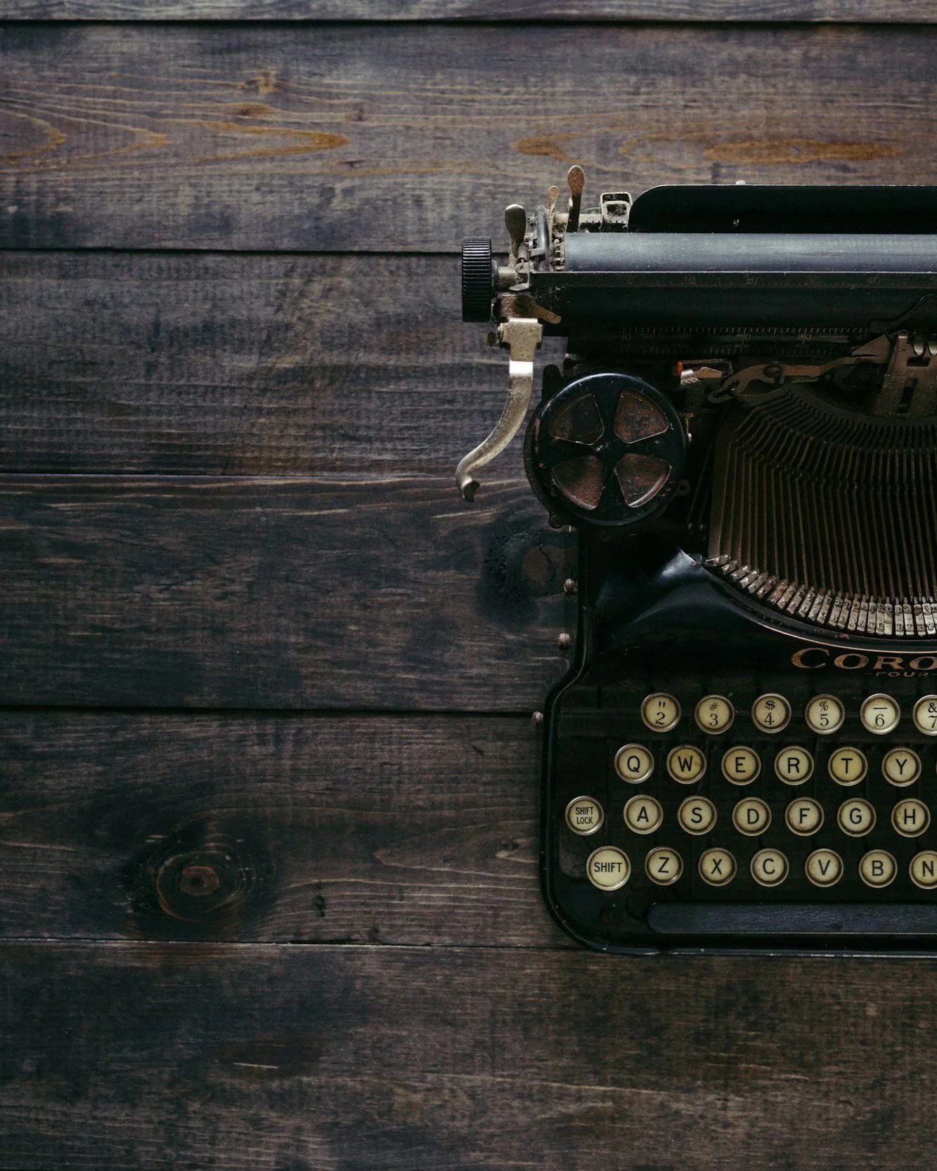 An old vintage typewriter placed on a dark wooden surface.