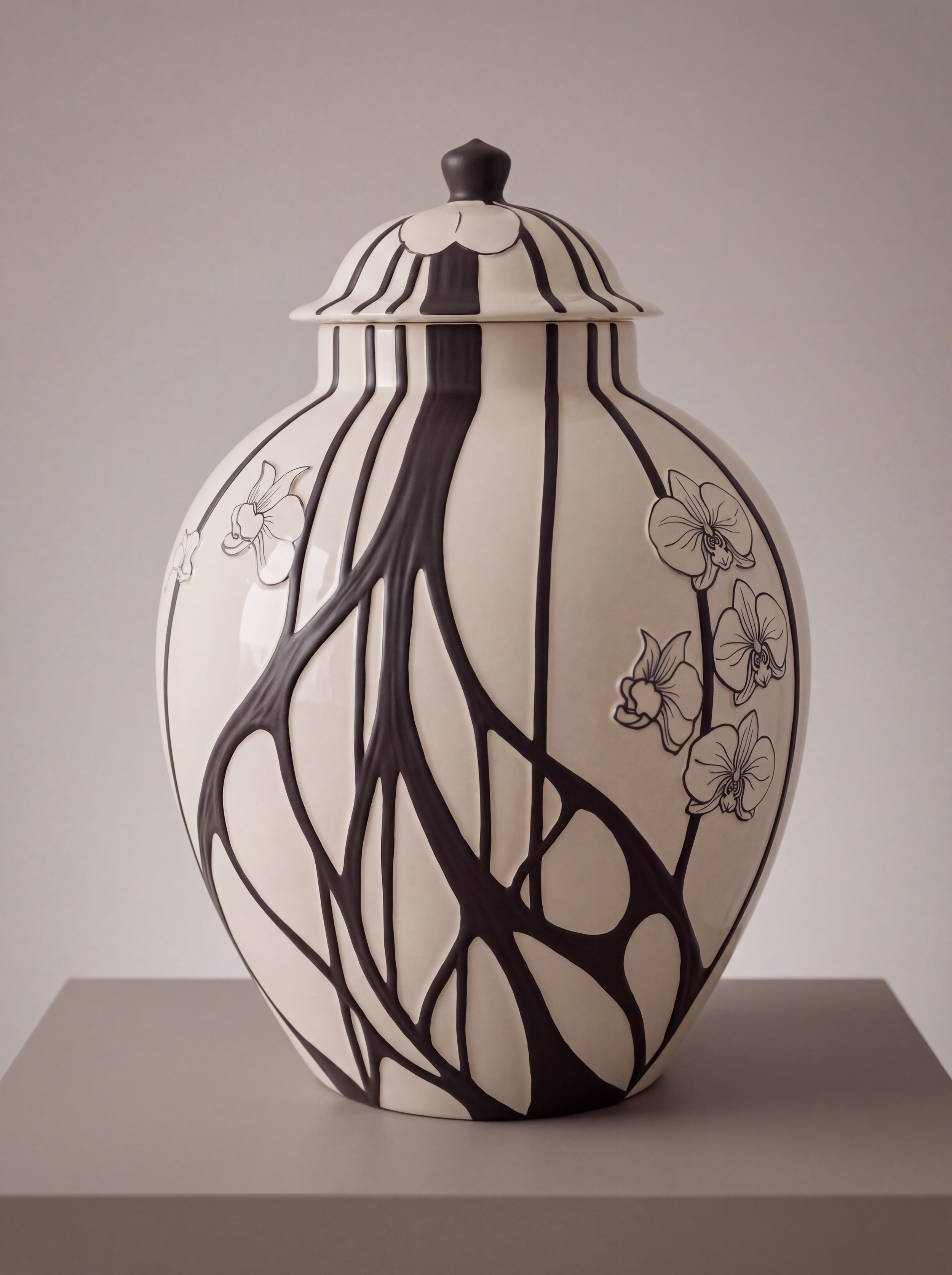 A black and white ceramic vase with floral and vine patterns, featuring black lines and orchids on a light background.