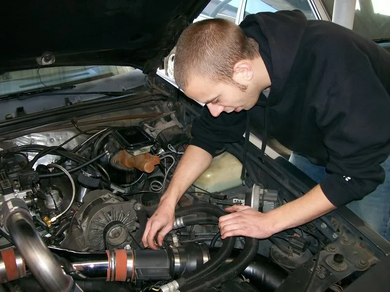 Man working on Buick T-type 3.8 V6 engine in a garage