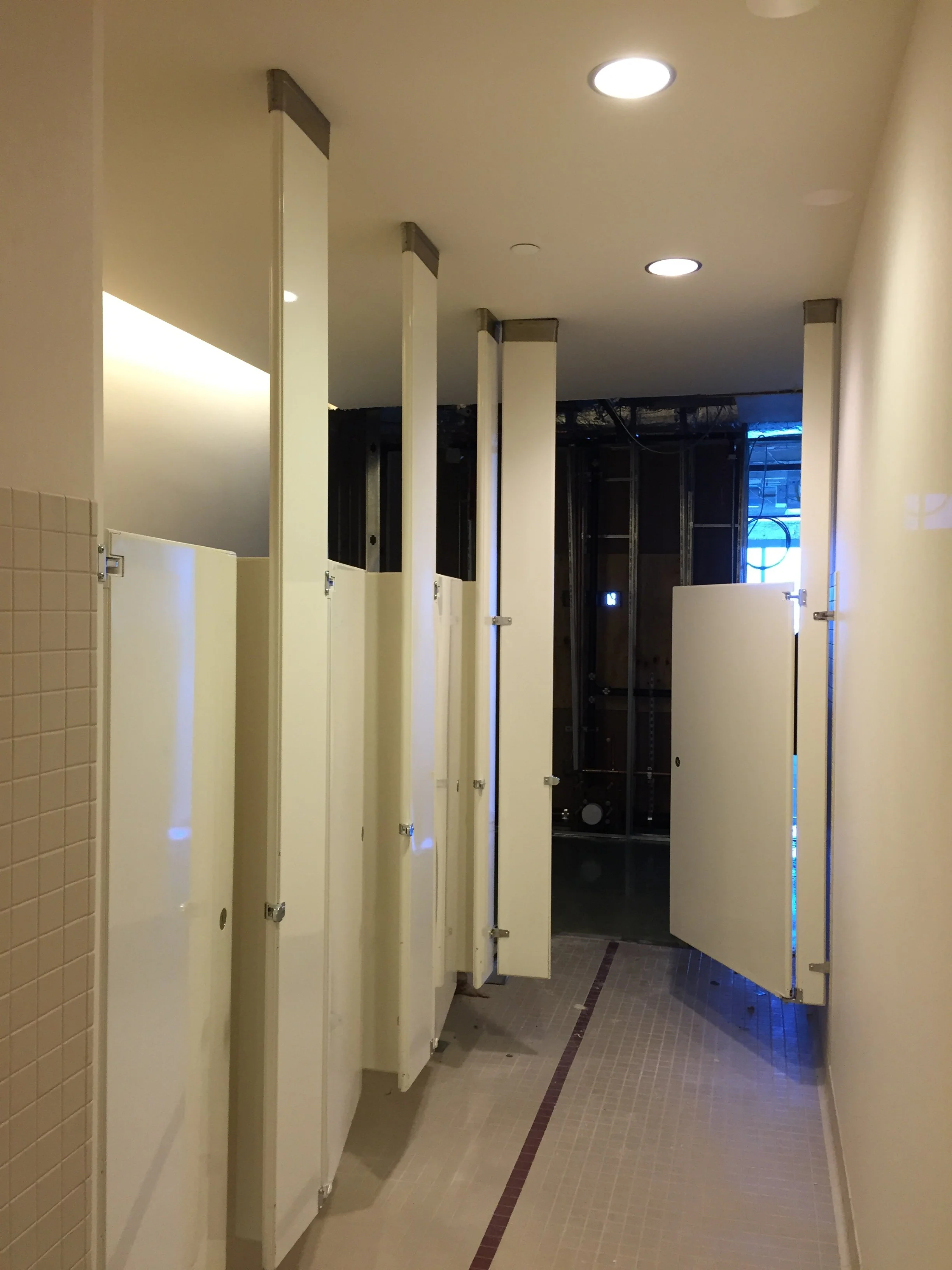 Public restroom with stalls, some doors open, and tiled floor.